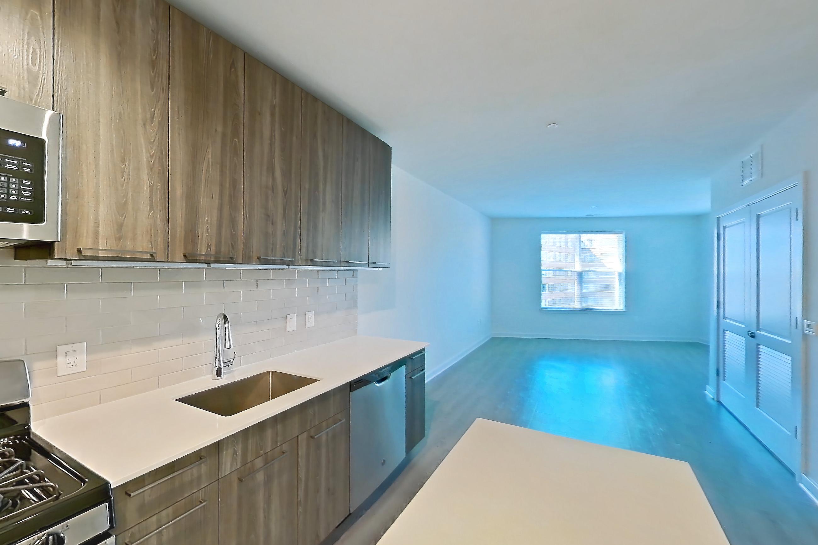 Kitchen with dishwasher, gas range, light countertops, light wood-finish flooring, microwave, oven/range, refrigerator, and stainless steel appliances, Apartment 605S at Cortland Columbia Pike