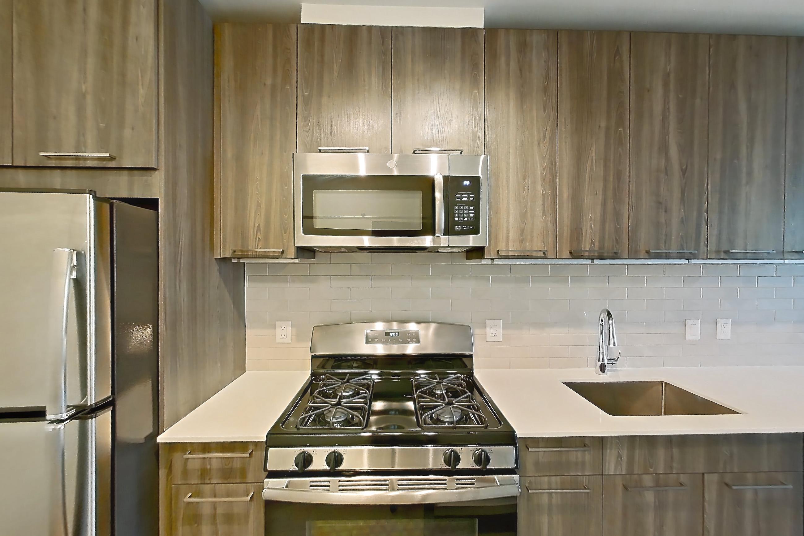 Kitchen with dishwasher, gas range, light countertops, light wood-finish flooring, microwave, oven/range, refrigerator, and stainless steel appliances, Apartment 605S at Cortland Columbia Pike