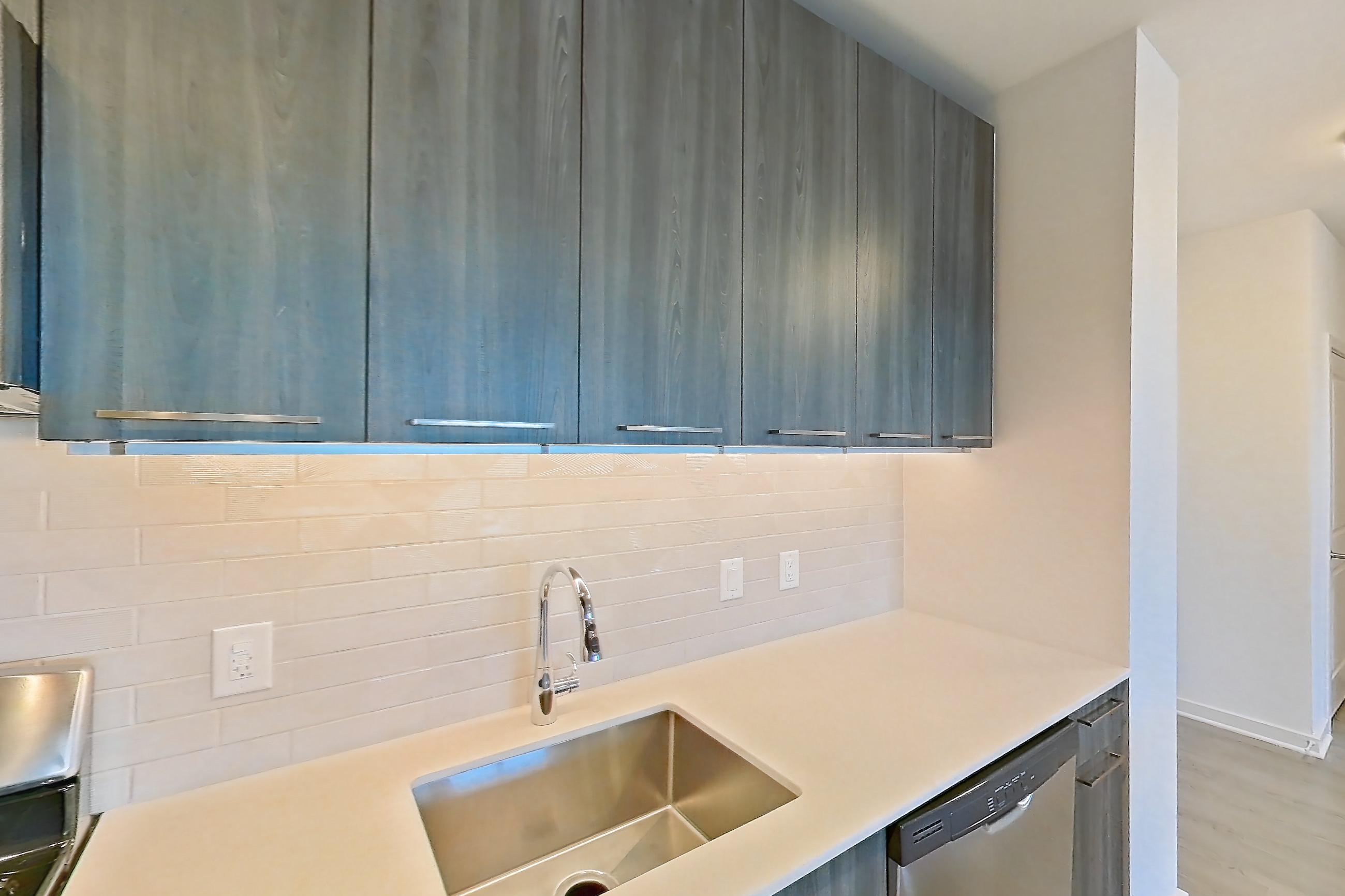 Kitchen with gas range, light countertops, light stone countertops, light wood-finish flooring, microwave, oven/range, refrigerator, and stainless steel appliances, Apartment 633S at Cortland Columbia Pike