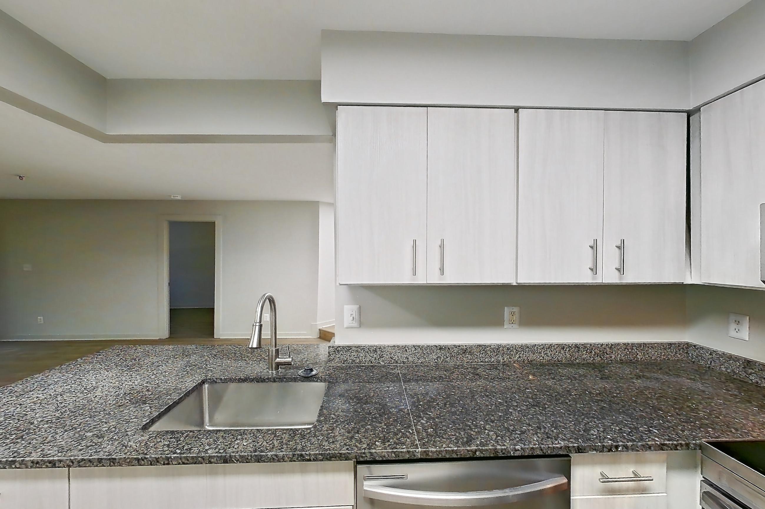 Kitchen with dark stone countertops, dishwasher, electric range, light wood-finish flooring, oven/range, range hood, refrigerator, and stainless steel appliances, Apartment 5812 at Cortland Manassas