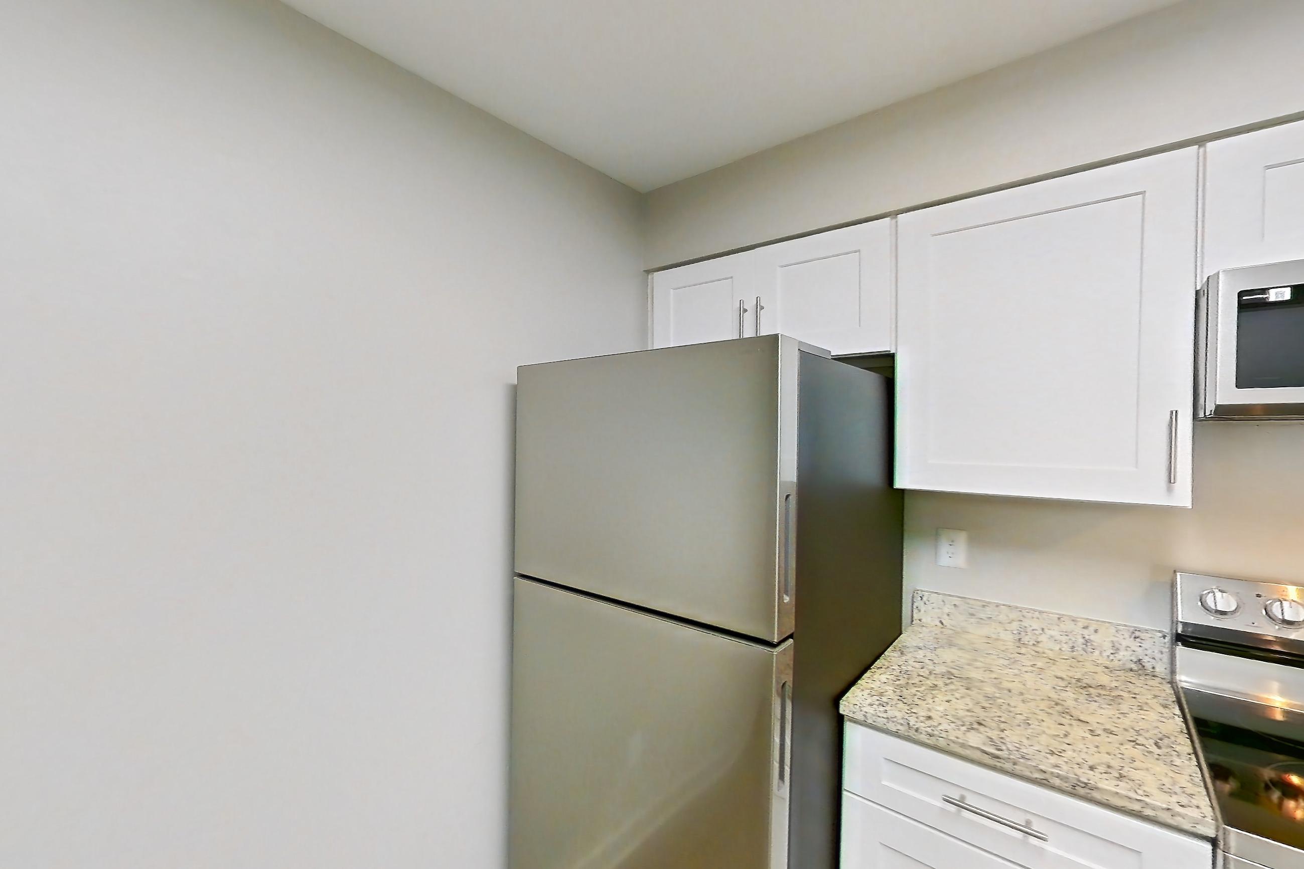 Kitchen with dishwasher, electric range, light countertops, light stone countertops, light wood-finish flooring, microwave, oven/range, refrigerator, and stainless steel appliances, Apartment 8521 at Cortland Manassas