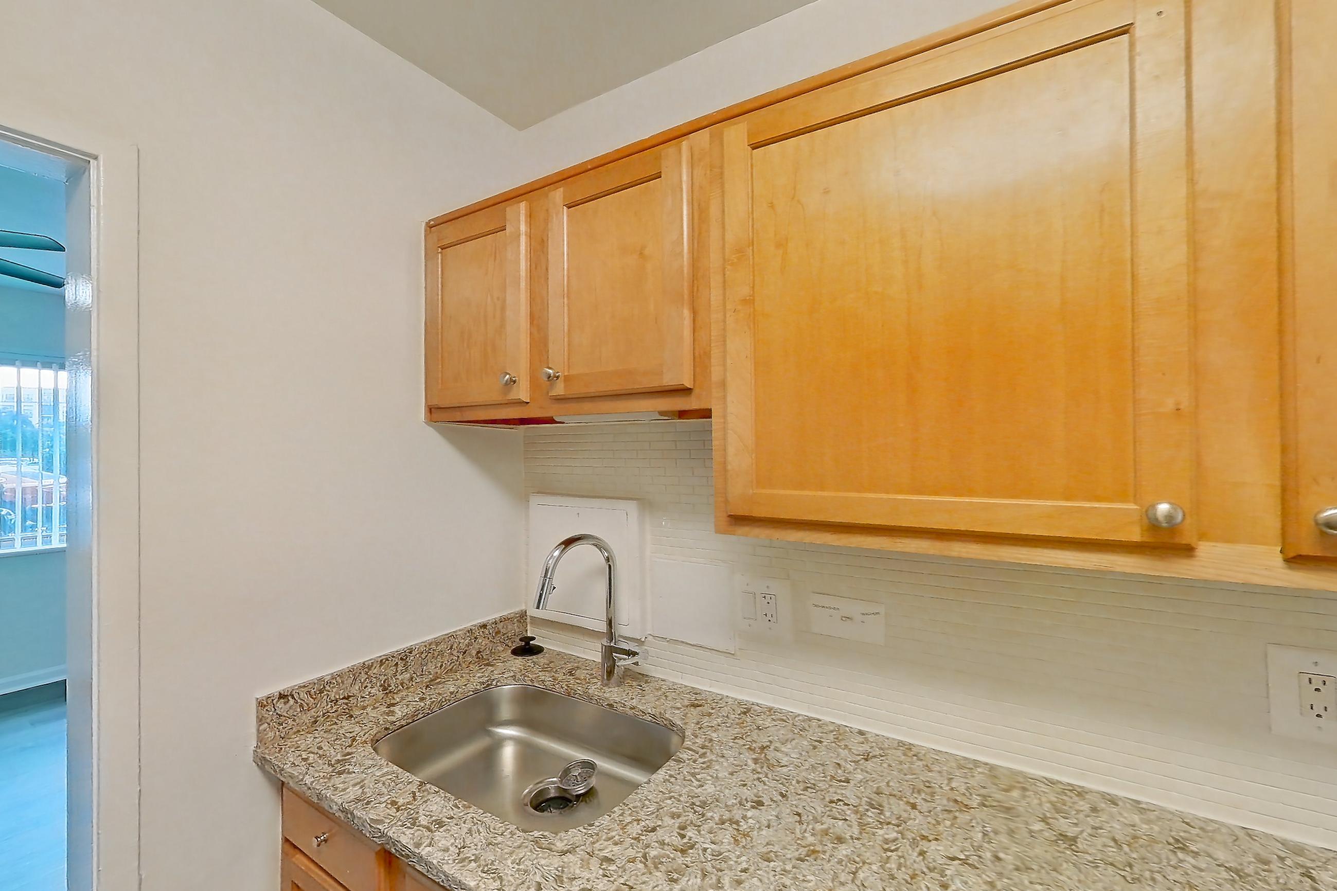Kitchen with dark wood-finish flooring, dishwasher, gas range, light countertops, light stone countertops, microwave, oven/range, refrigerator, and stainless steel appliances, Apartment N-129 at Cortland on Pike