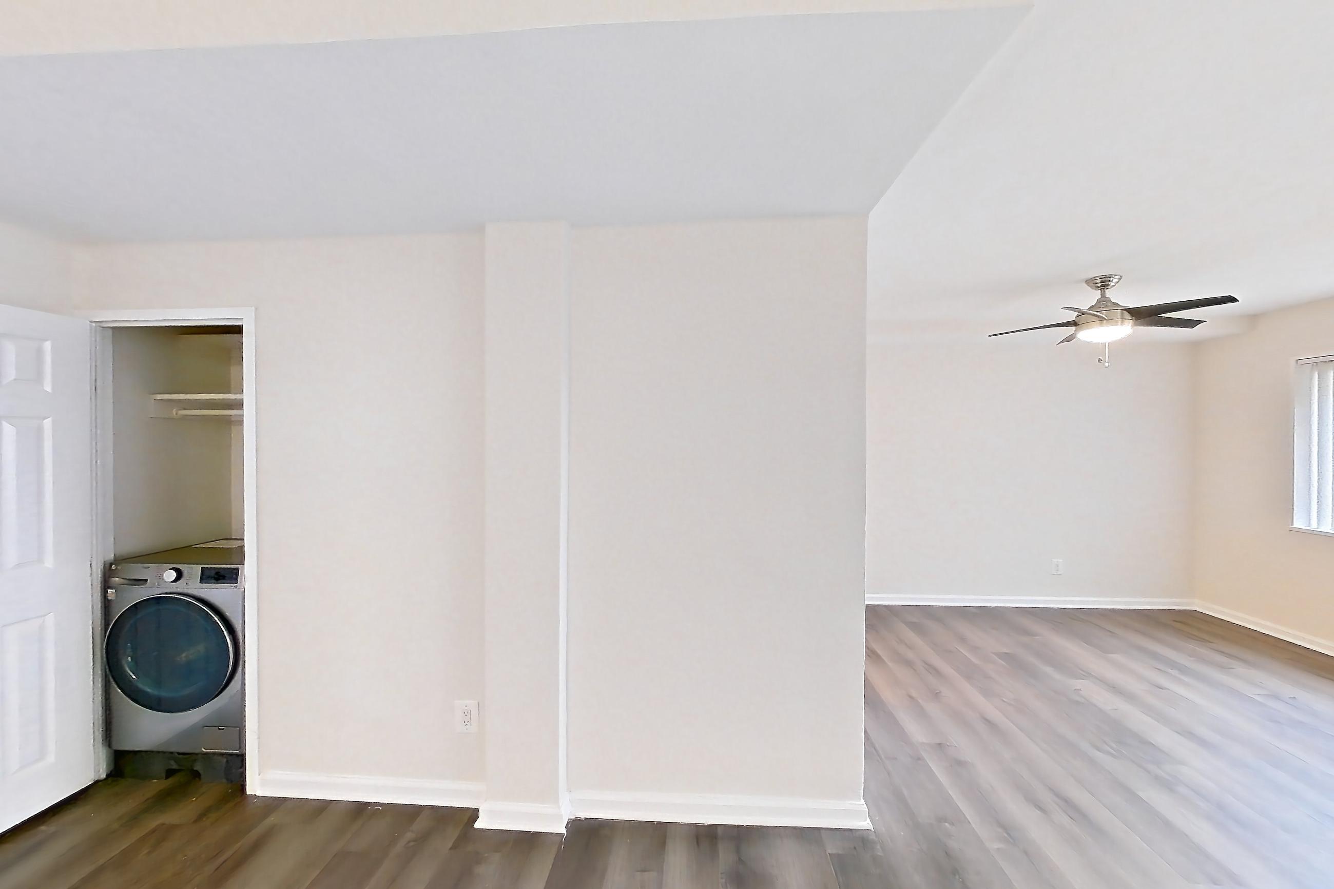 Living room with dark wood-finish flooring and in-unit laundry, Apartment N-129 at Cortland on Pike