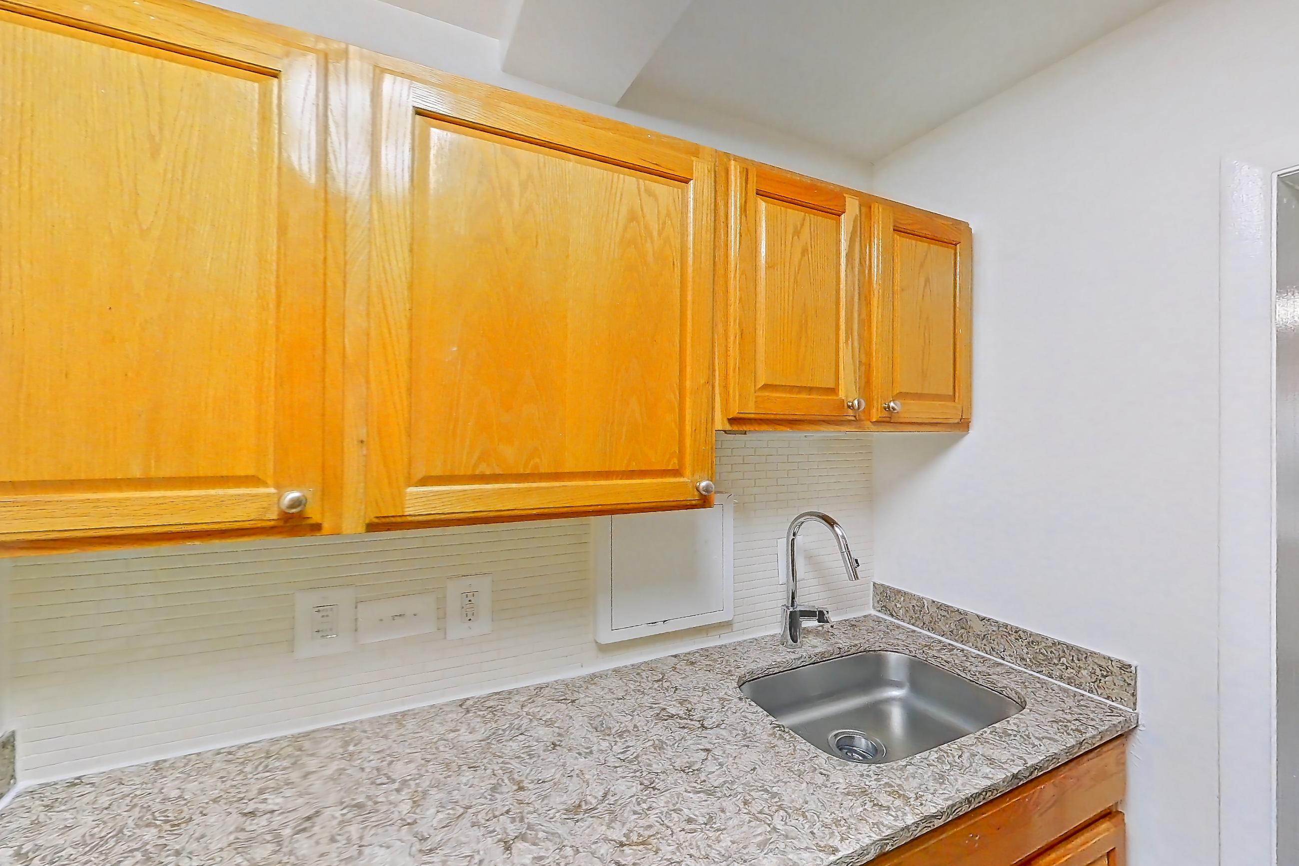 Kitchen with dishwasher, gas range, in-unit laundry, light countertops, light stone countertops, light wood-finish flooring, microwave, oven/range, refrigerator, and stainless steel appliances, Apartment C-209 at Cortland on Pike