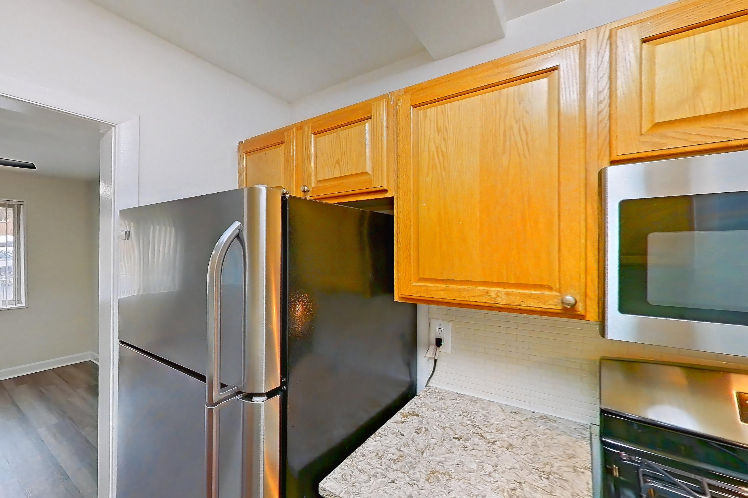 Kitchen with dishwasher, gas range, in-unit laundry, light countertops, light stone countertops, light wood-finish flooring, microwave, oven/range, refrigerator, and stainless steel appliances, Apartment C-209 at Cortland on Pike