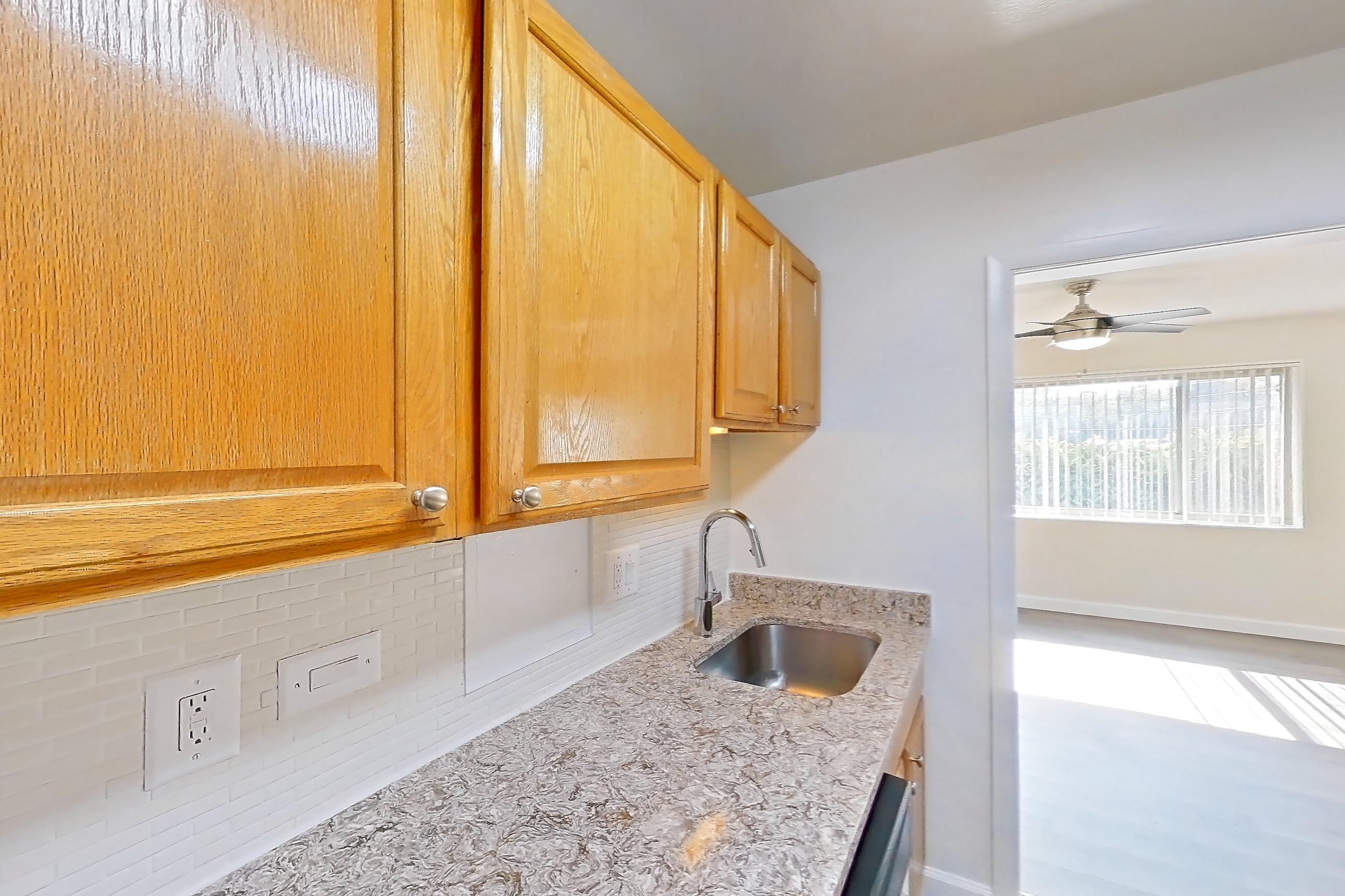 Kitchen with dark wood-finish flooring, dishwasher, gas range, light countertops, light stone countertops, microwave, oven/range, refrigerator, and stainless steel appliances, Apartment C-333 at Cortland on Pike
