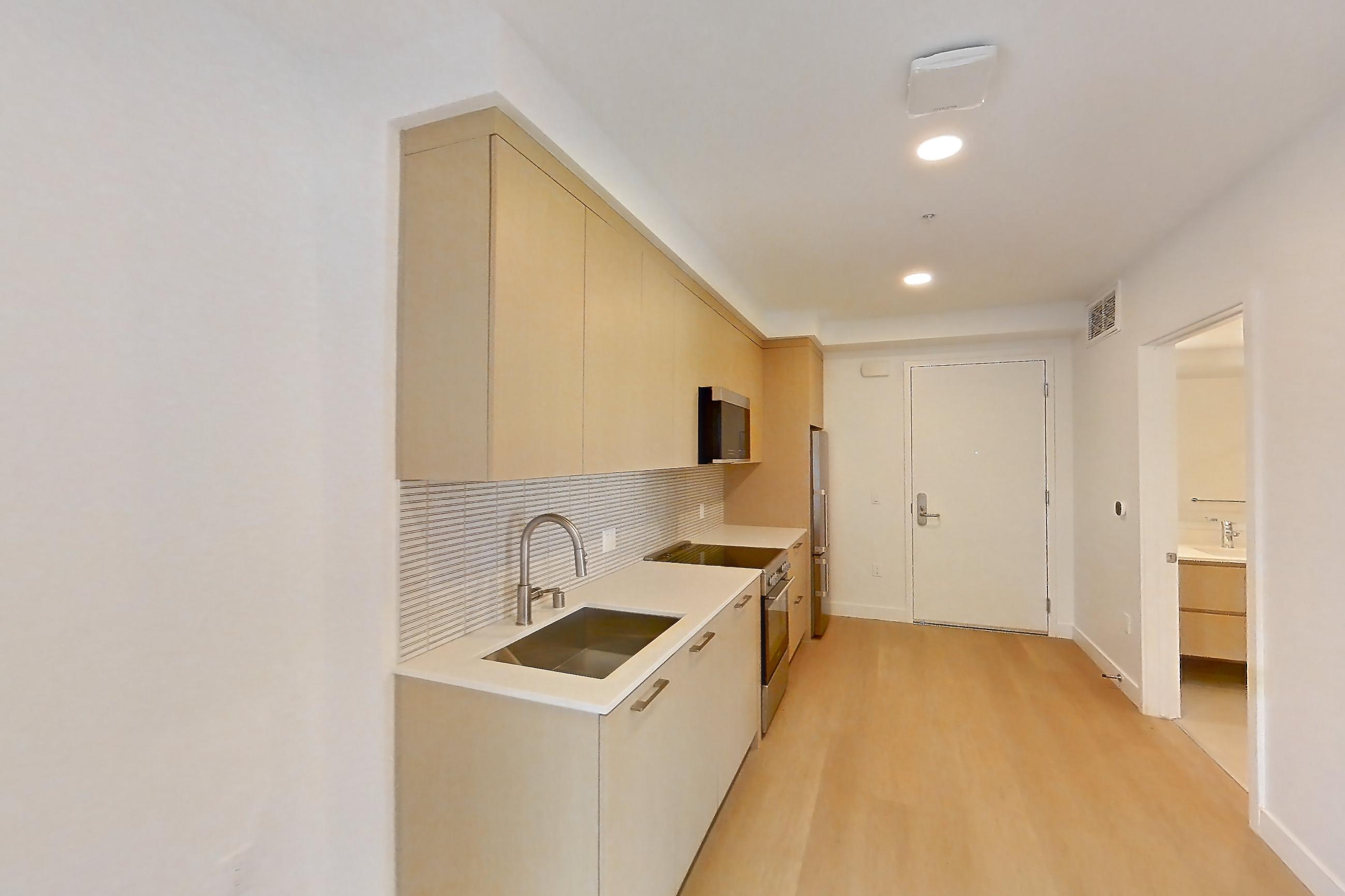Living room with electric range, light wood-finish flooring, oven/range, and stainless steel appliances, Apartment B-708 at Santa Monica Collection