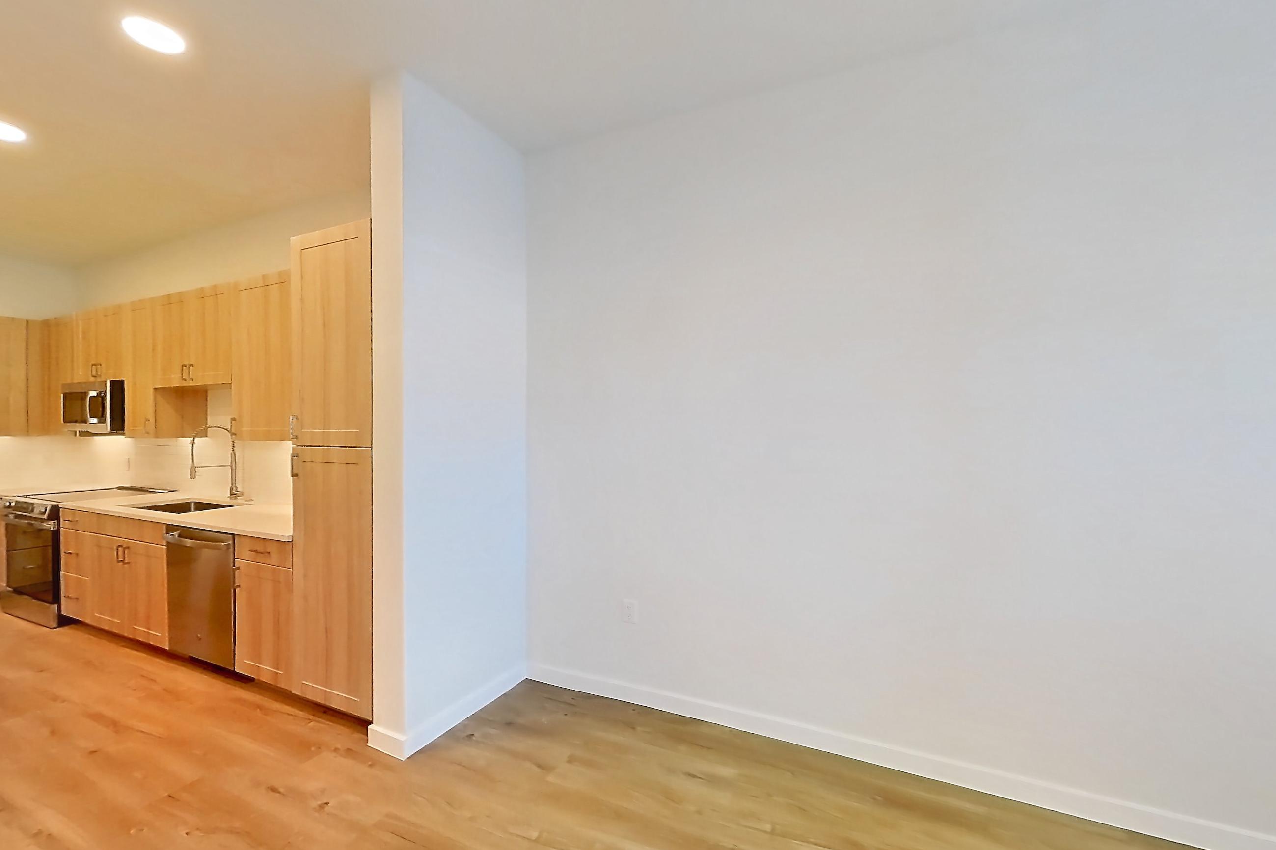 Living space with dishwasher, electric range, light countertops, light wood-finish flooring, oven/range, refrigerator, and stainless steel appliances, Apartment 115 at Lantower Bayside