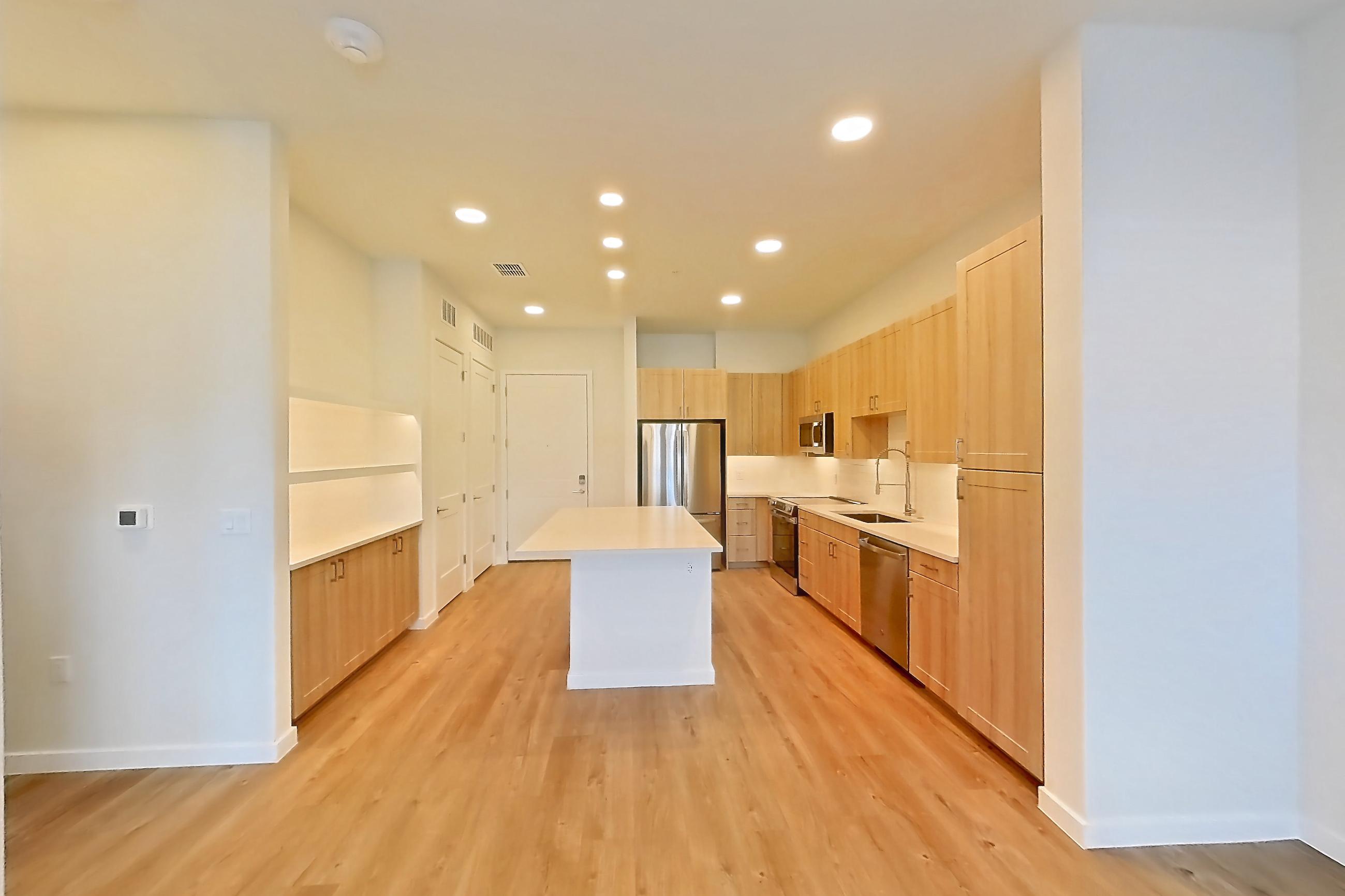 Living space with dishwasher, electric range, light countertops, light wood-finish flooring, oven/range, refrigerator, and stainless steel appliances, Apartment 115 at Lantower Bayside
