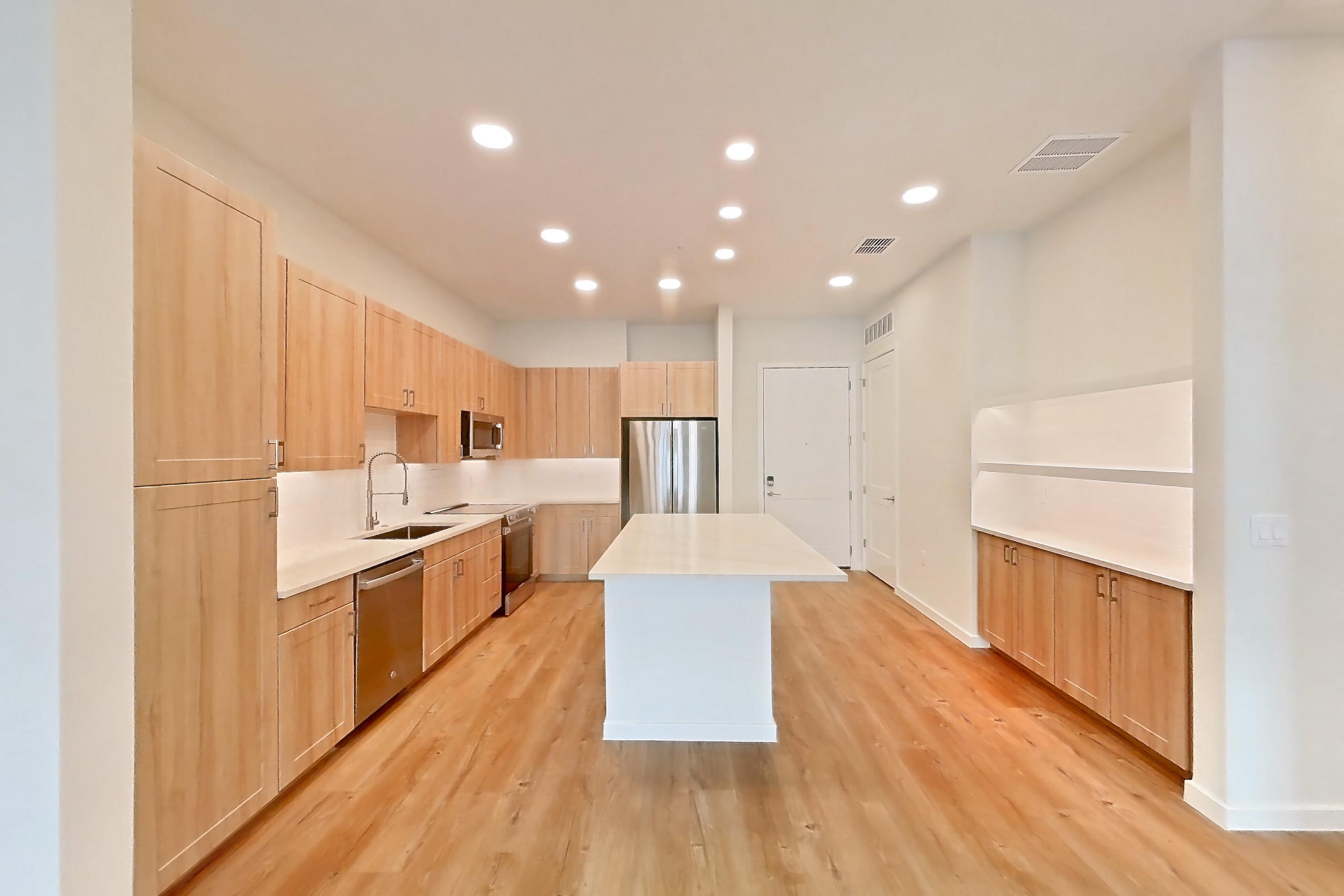 Living space with dishwasher, electric range, light countertops, light wood-finish flooring, oven/range, refrigerator, and stainless steel appliances, Apartment 156 at Lantower Bayside