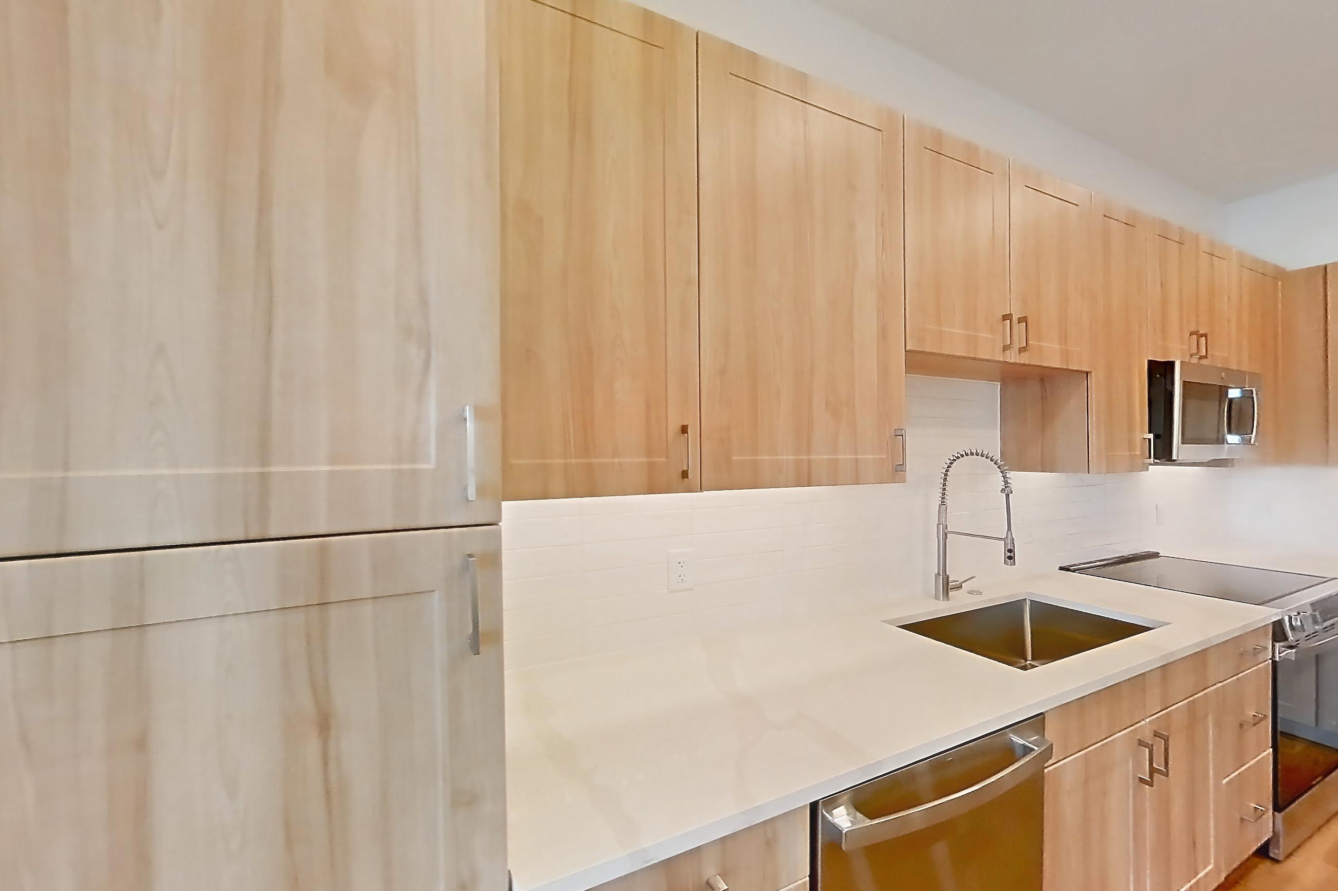 Kitchen with dishwasher, electric range, light countertops, light stone countertops, light wood-finish flooring, microwave, oven/range, refrigerator, and stainless steel appliances, Apartment 233 at Lantower Bayside