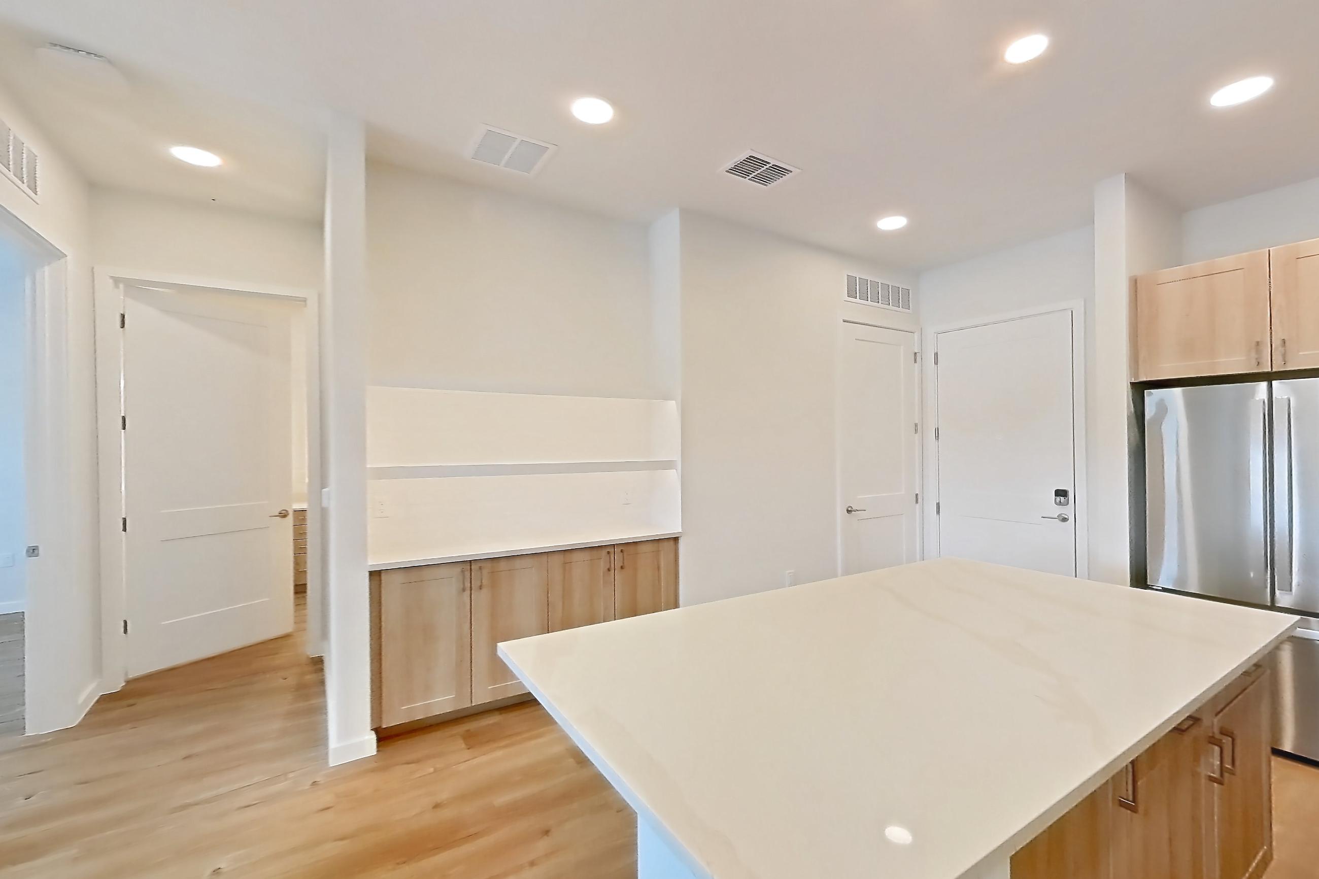 Kitchen with dishwasher, electric range, light countertops, light stone countertops, light wood-finish flooring, microwave, oven/range, refrigerator, and stainless steel appliances, Apartment 235 at Lantower Bayside