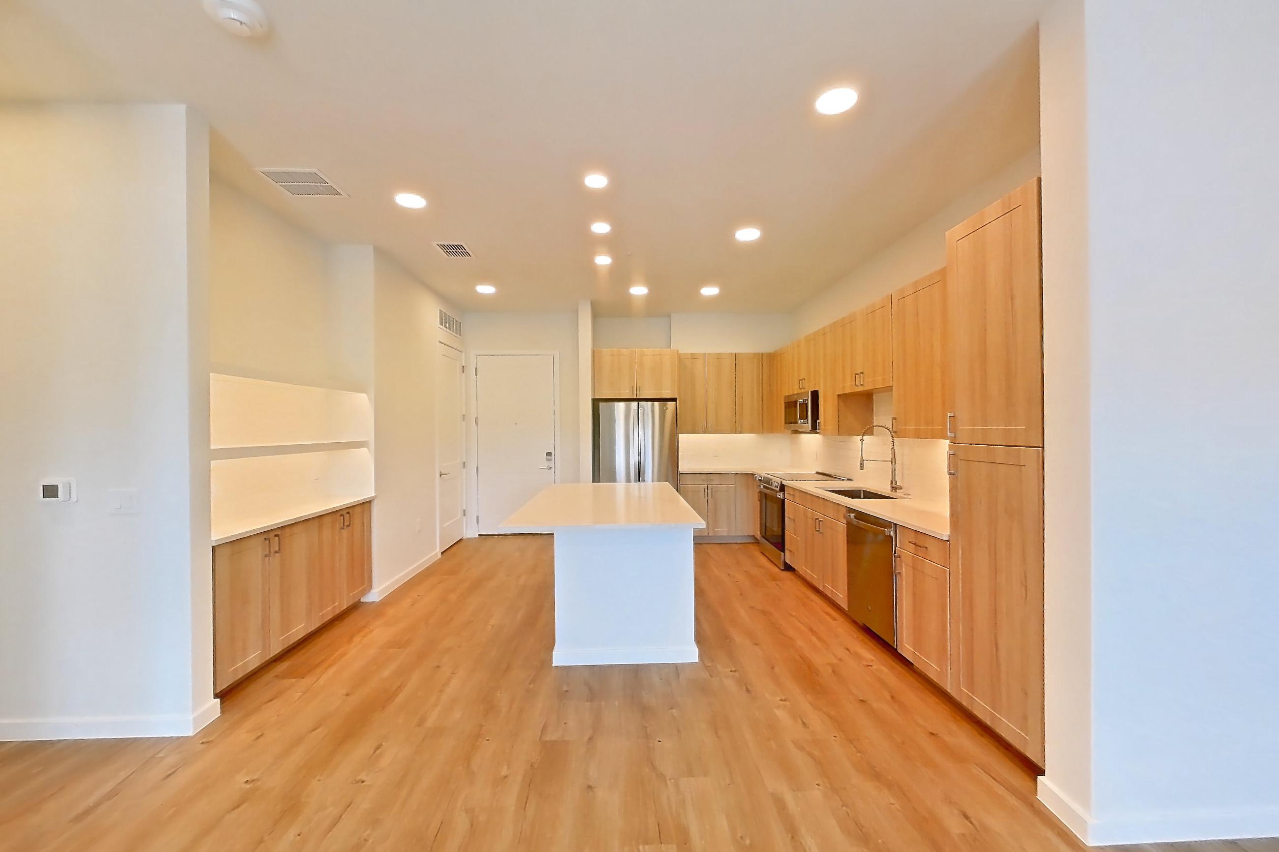 Living space with dishwasher, electric range, light countertops, light wood-finish flooring, oven/range, refrigerator, and stainless steel appliances, Apartment 235 at Lantower Bayside