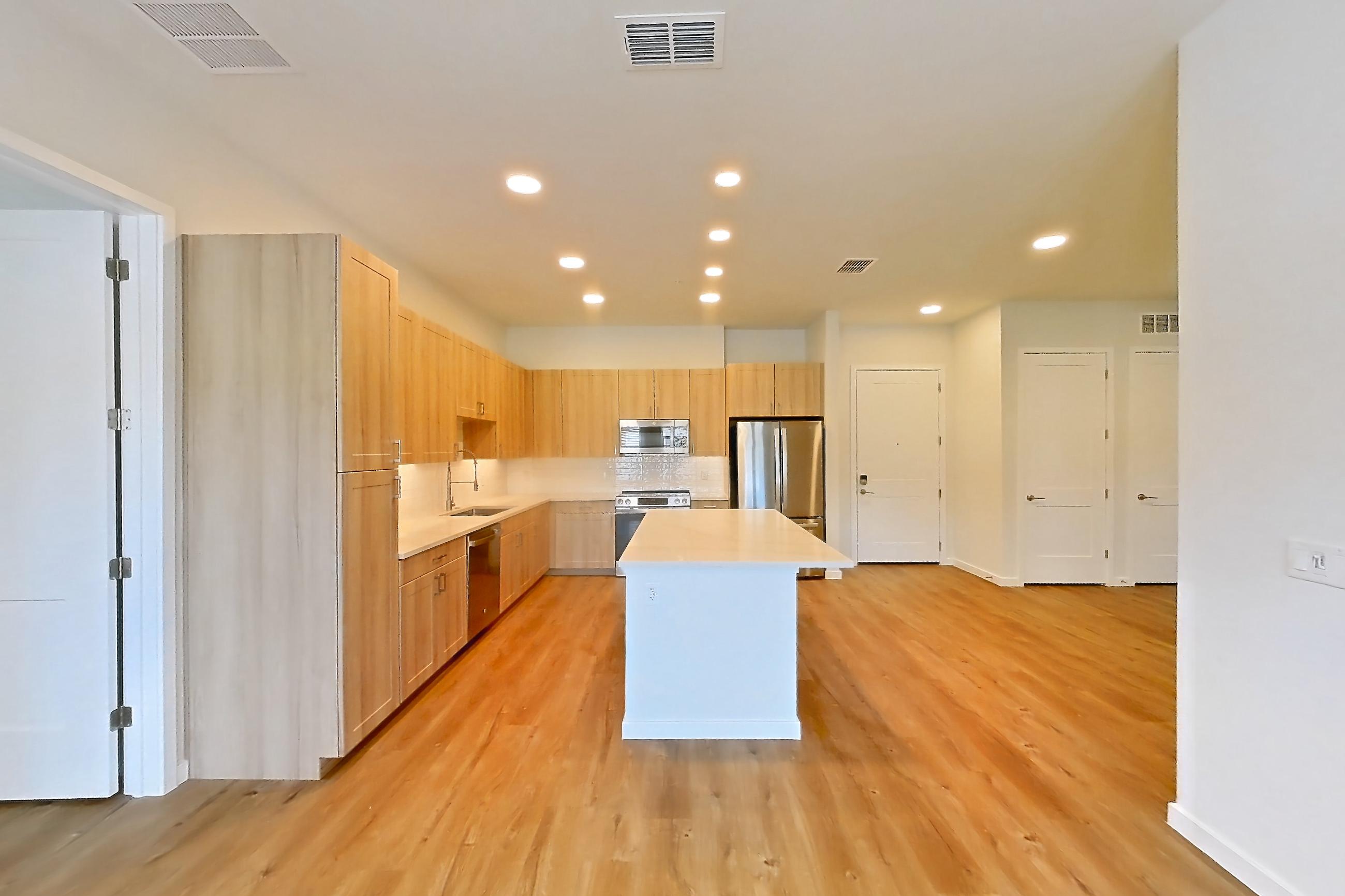 Living space with dishwasher, light countertops, light wood-finish flooring, oven/range, refrigerator, and stainless steel appliances, Apartment 239 at Lantower Bayside