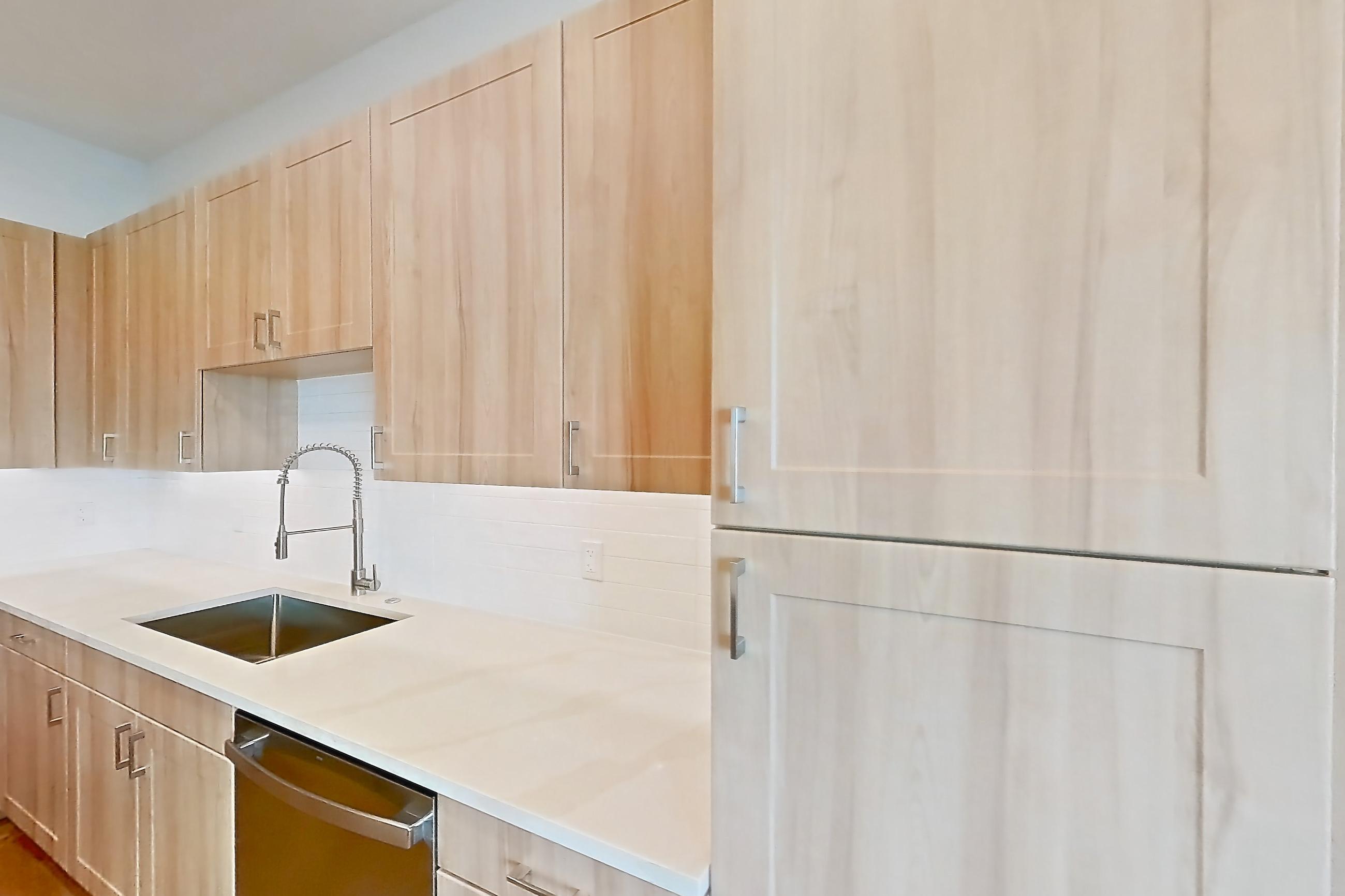 Kitchen with dishwasher, electric range, light countertops, light stone countertops, light wood-finish flooring, microwave, oven/range, refrigerator, and stainless steel appliances, Apartment 242 at Lantower Bayside