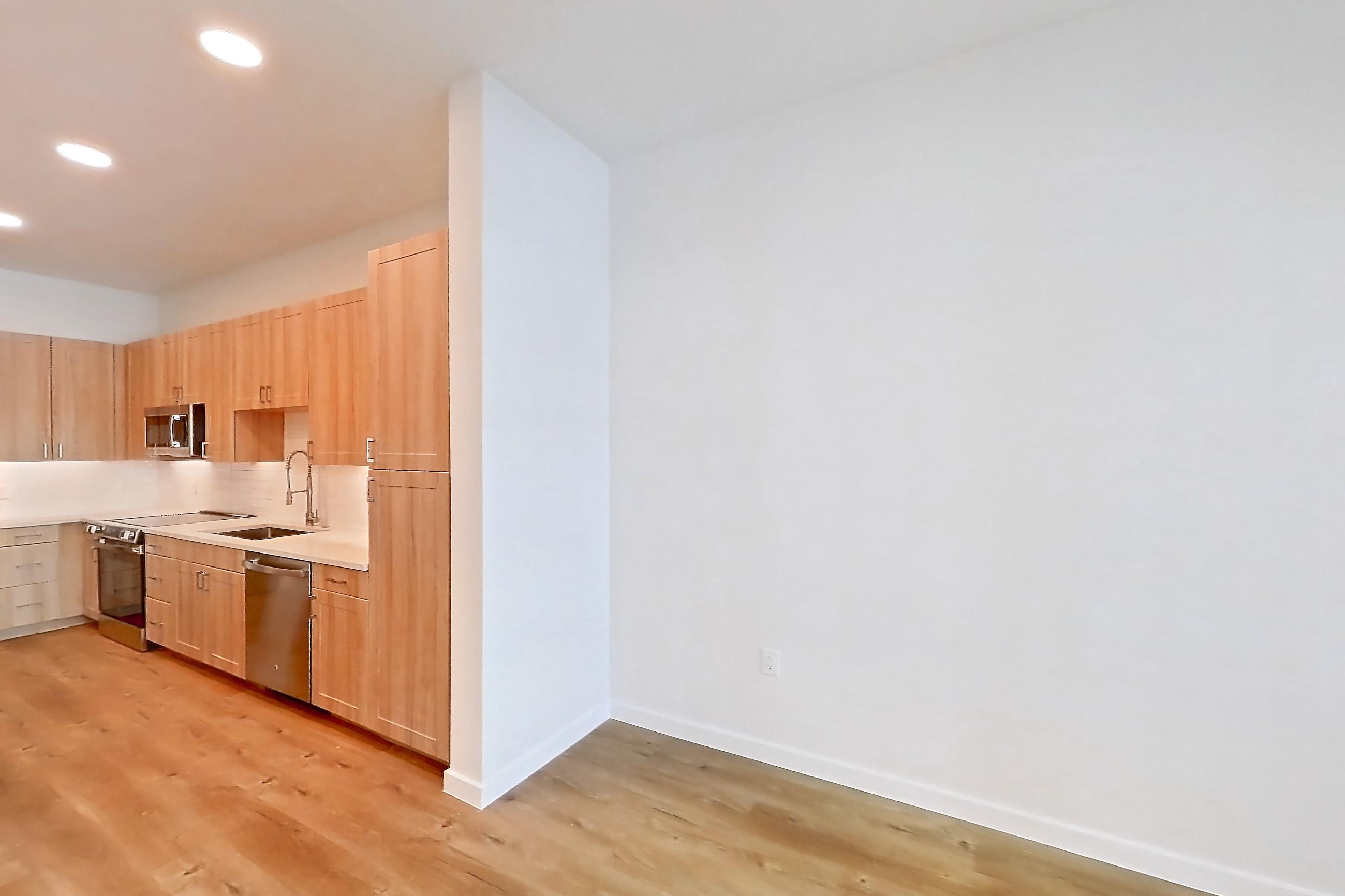 Living space with dishwasher, electric range, light stone countertops, light wood-finish flooring, oven/range, refrigerator, and stainless steel appliances, Apartment 248 at Lantower Bayside