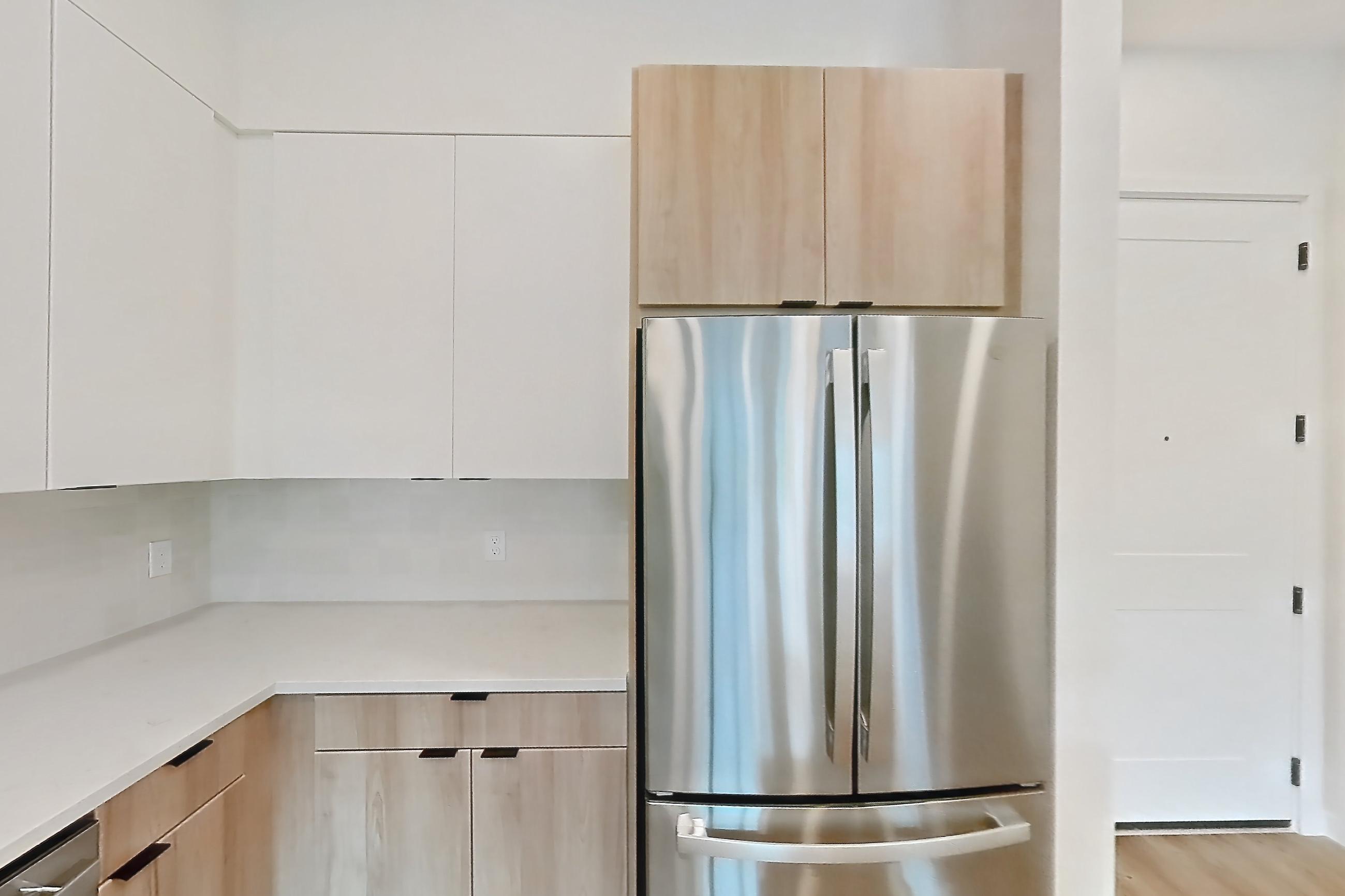 Kitchen with electric range, light countertops, light stone countertops, light wood-finish flooring, microwave, oven/range, refrigerator, and stainless steel appliances, Apartment 240 at Lantower Sunrise
