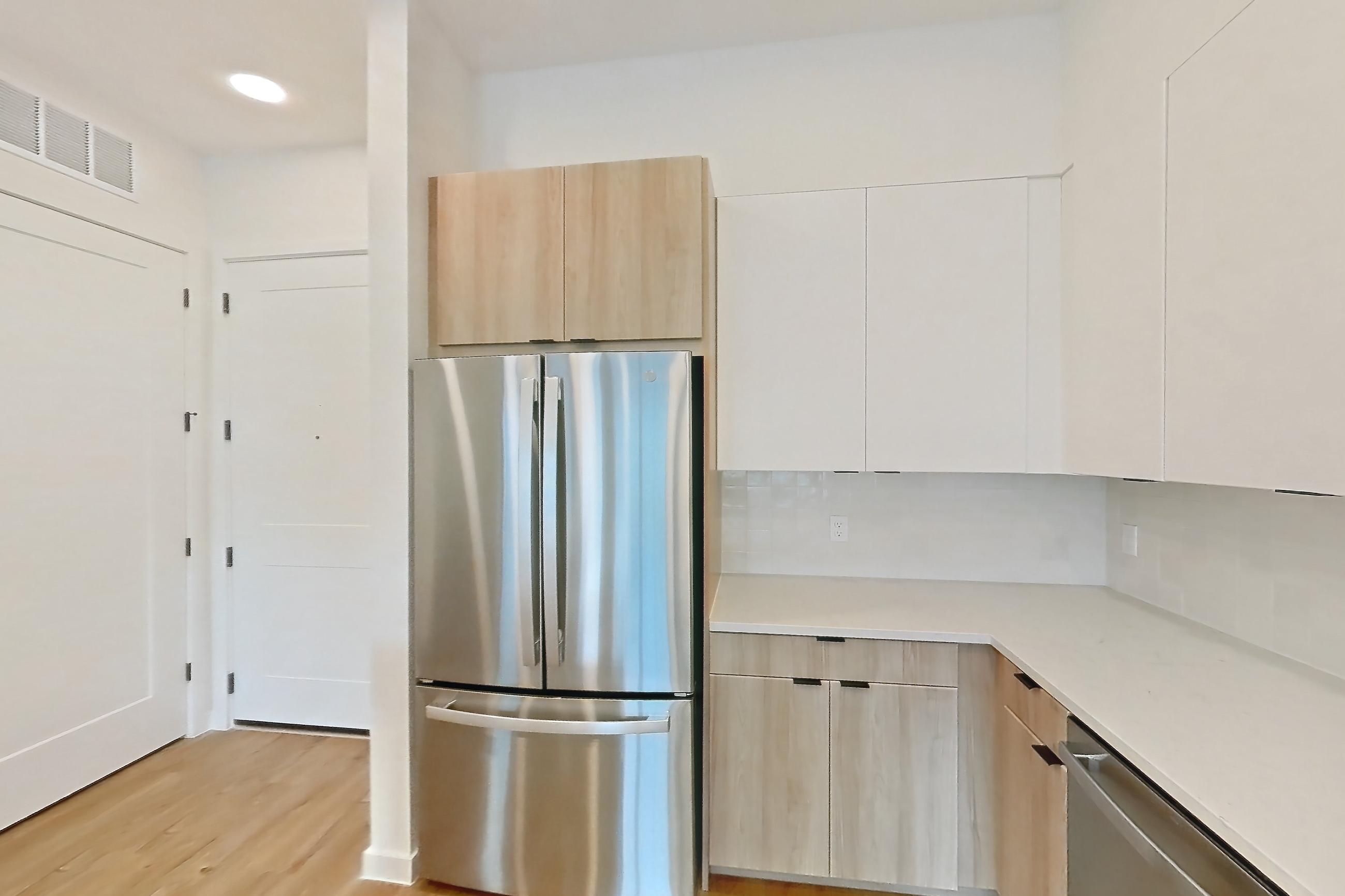 Kitchen with electric range, light countertops, light stone countertops, light wood-finish flooring, microwave, oven/range, refrigerator, and stainless steel appliances, Apartment 338 at Lantower Sunrise