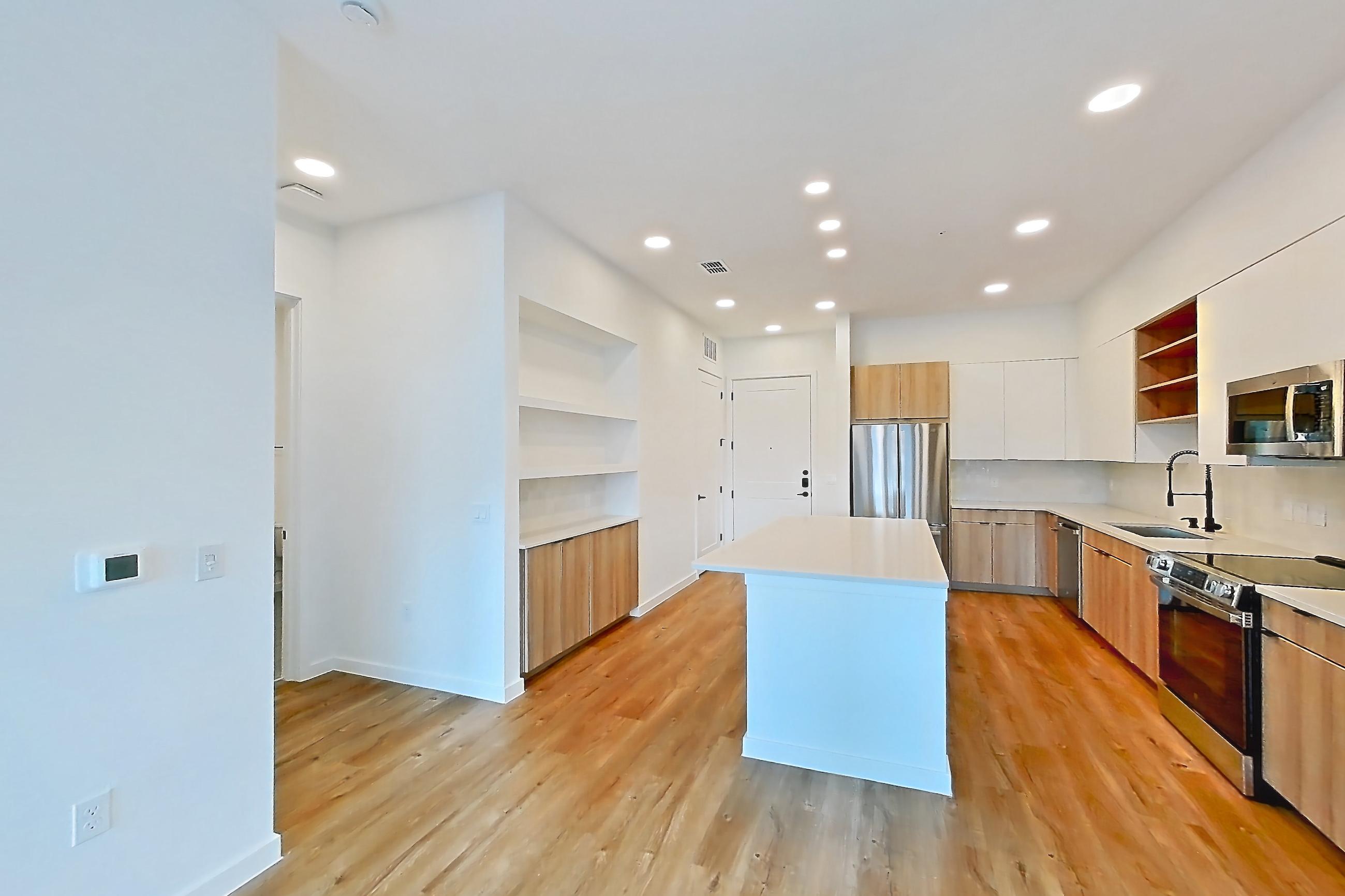 Living room with baseboard heating, electric range, light countertops, light wood-finish flooring, oven/range, refrigerator, and stainless steel appliances, Apartment 338 at Lantower Sunrise