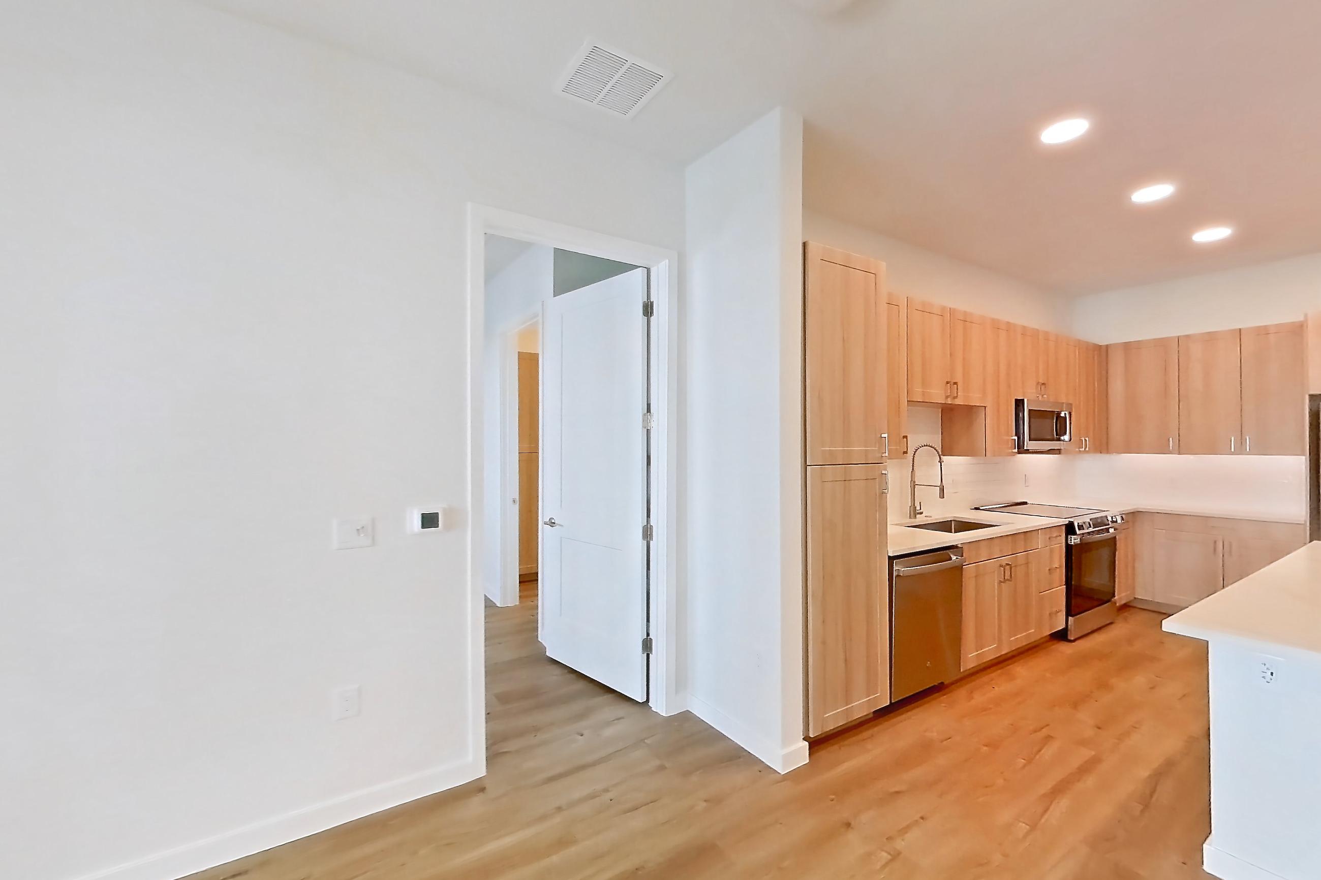 Living space with dishwasher, electric range, light countertops, light stone countertops, light wood-finish flooring, oven/range, refrigerator, and stainless steel appliances, Apartment 252 at Lantower Bayside
