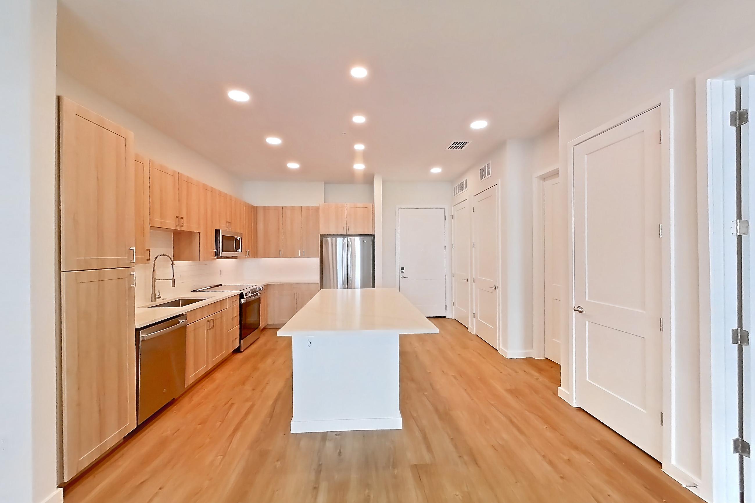 Living space with dishwasher, electric range, light countertops, light stone countertops, light wood-finish flooring, oven/range, refrigerator, and stainless steel appliances, Apartment 252 at Lantower Bayside