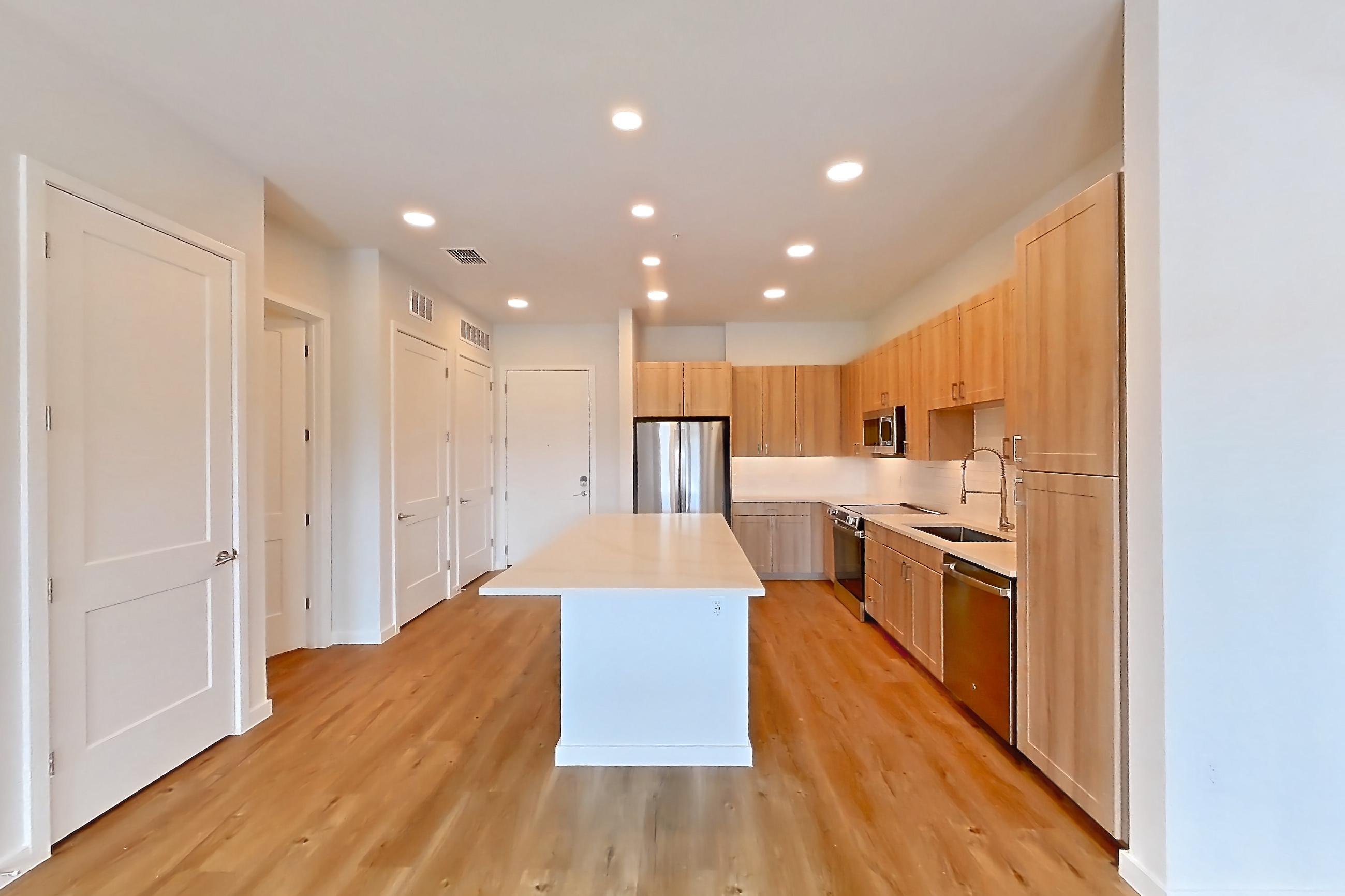 Living space with dishwasher, electric range, light stone countertops, light wood-finish flooring, oven/range, refrigerator, and stainless steel appliances, Apartment 253 at Lantower Bayside