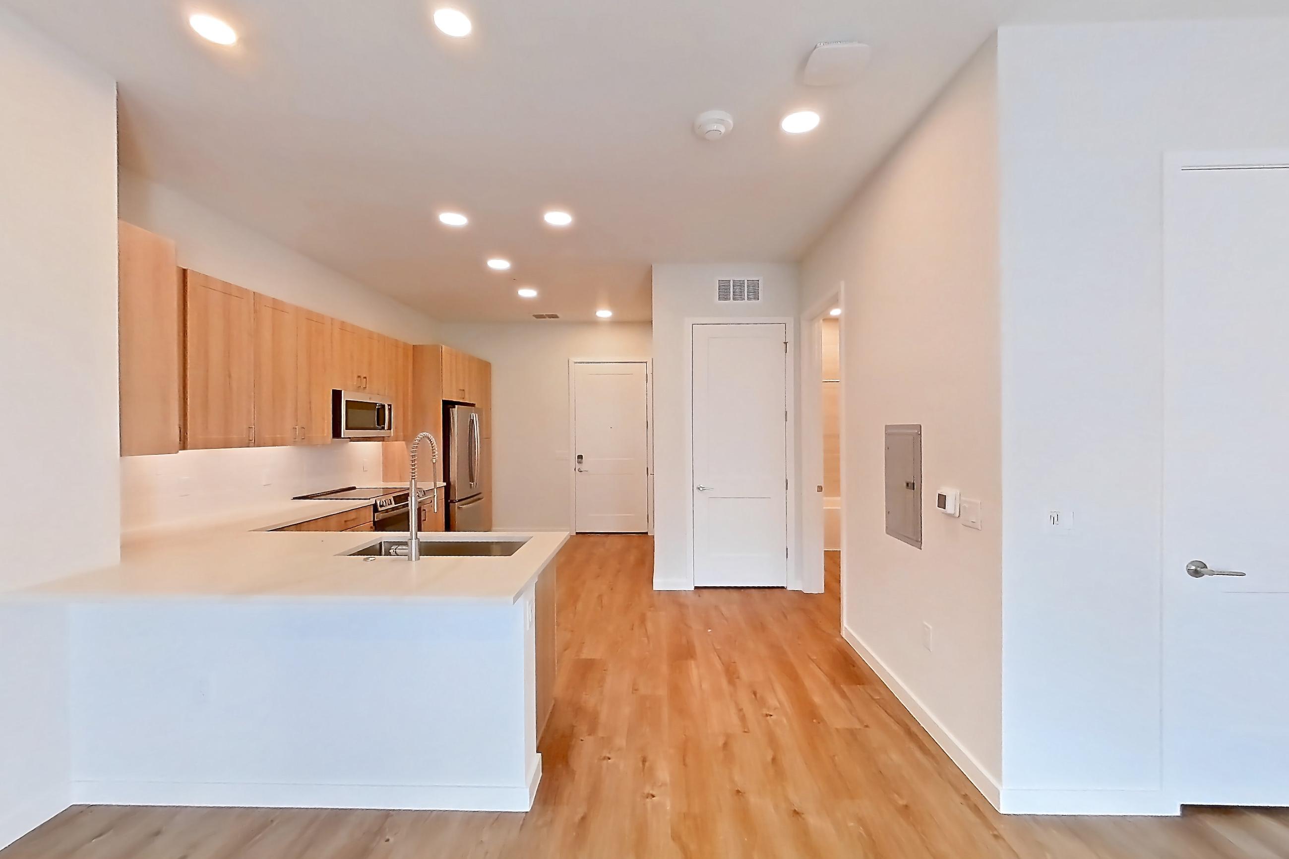 Living space with electric range, light stone countertops, light wood-finish flooring, oven/range, refrigerator, and stainless steel appliances, Apartment 260 at Lantower Bayside