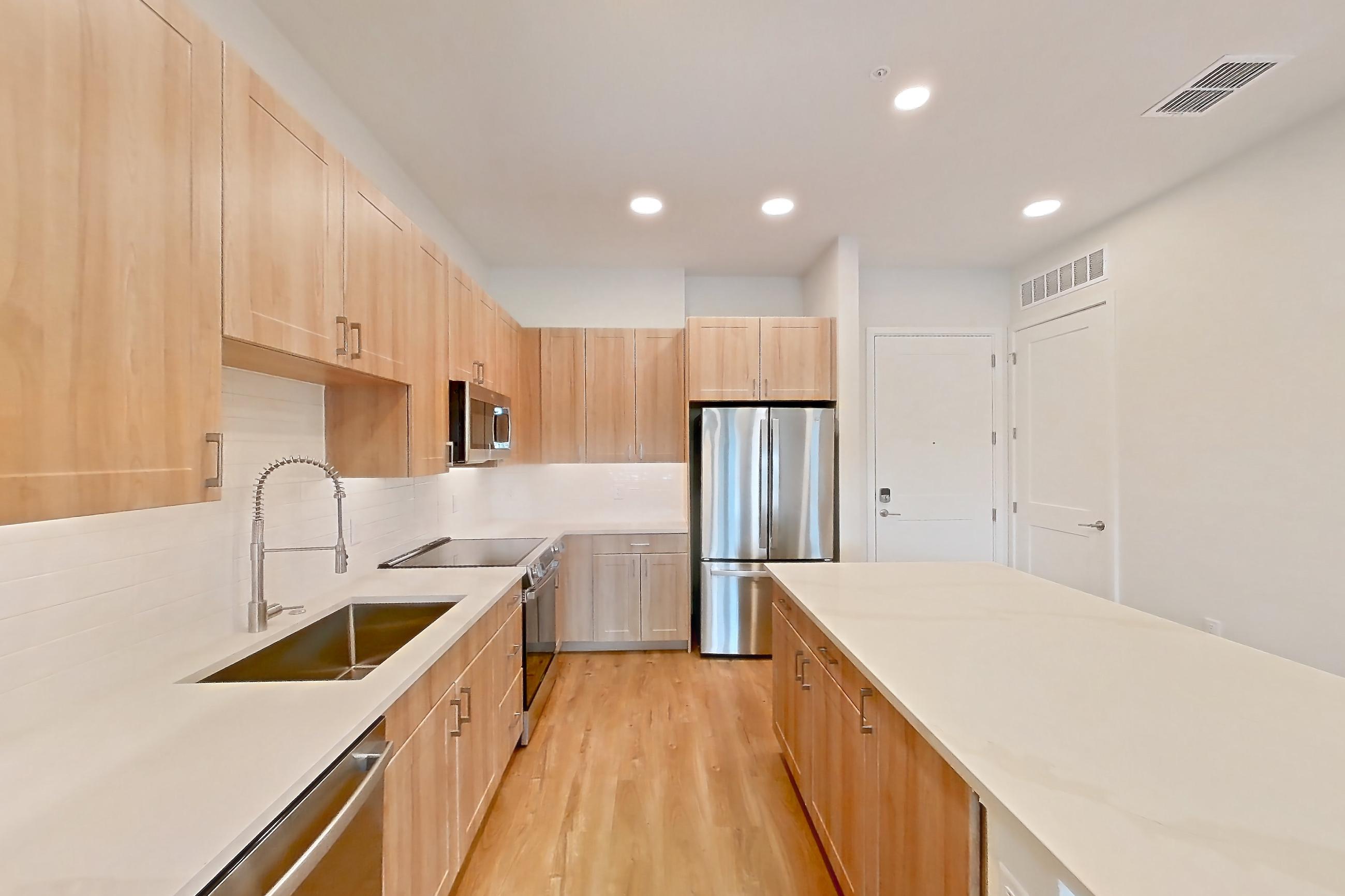 Kitchen with dishwasher, electric range, light countertops, light stone countertops, light wood-finish flooring, microwave, oven/range, refrigerator, and stainless steel appliances, Apartment 331 at Lantower Bayside
