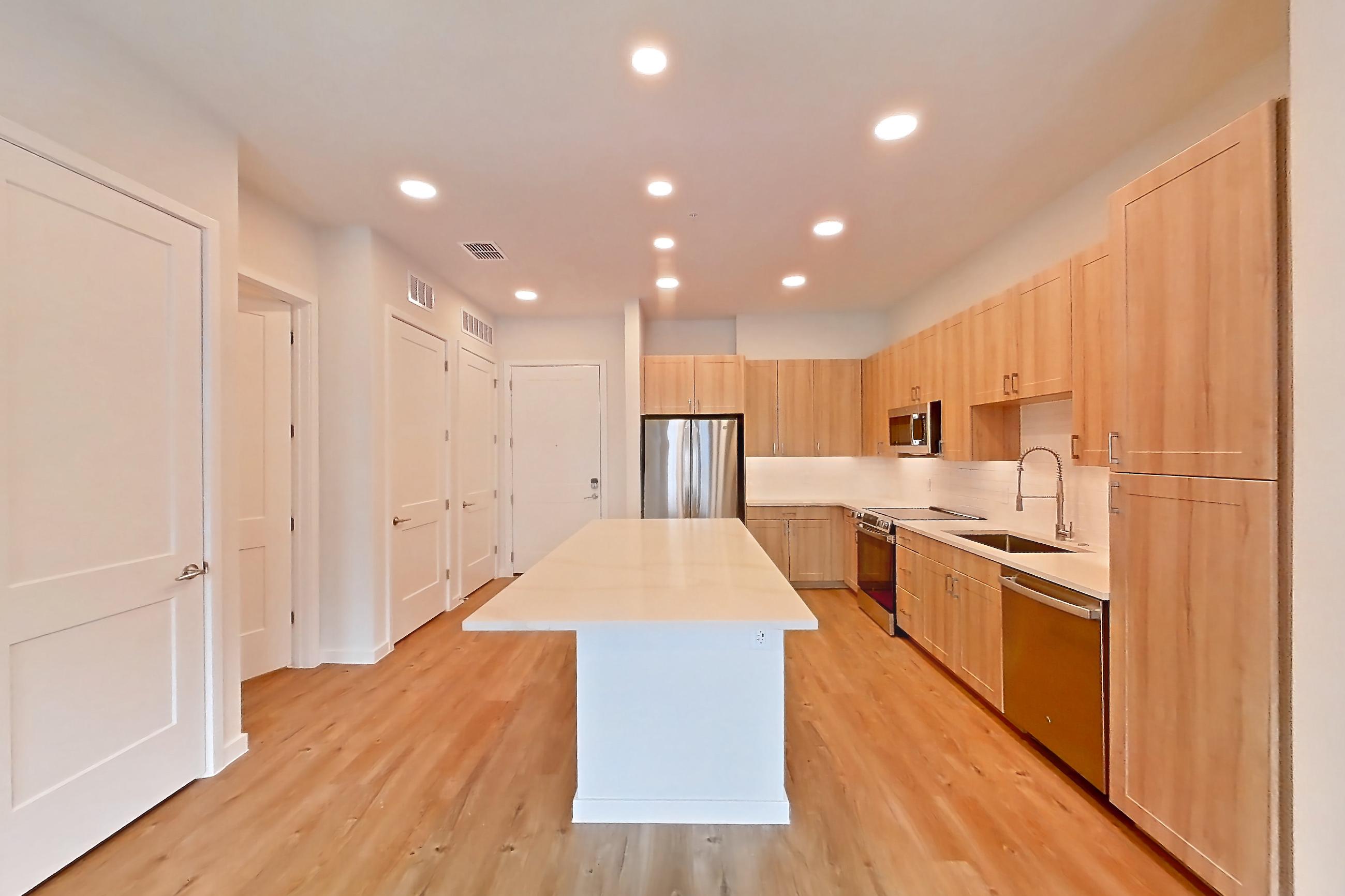 Living space with dishwasher, electric range, light countertops, light stone countertops, light wood-finish flooring, oven/range, refrigerator, and stainless steel appliances, Apartment 335 at Lantower Bayside