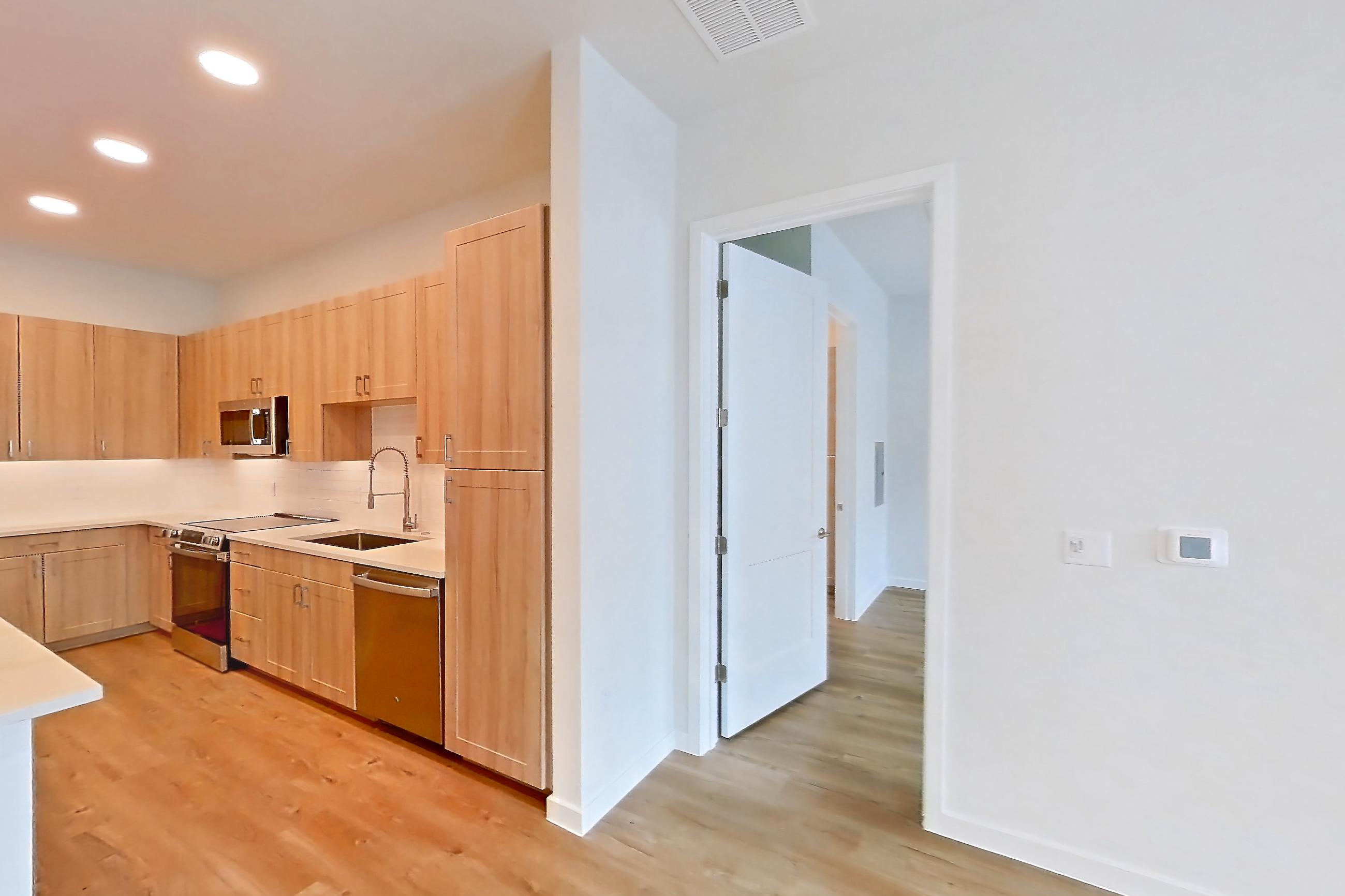 Living space with dishwasher, electric range, light countertops, light stone countertops, light wood-finish flooring, oven/range, refrigerator, and stainless steel appliances, Apartment 335 at Lantower Bayside