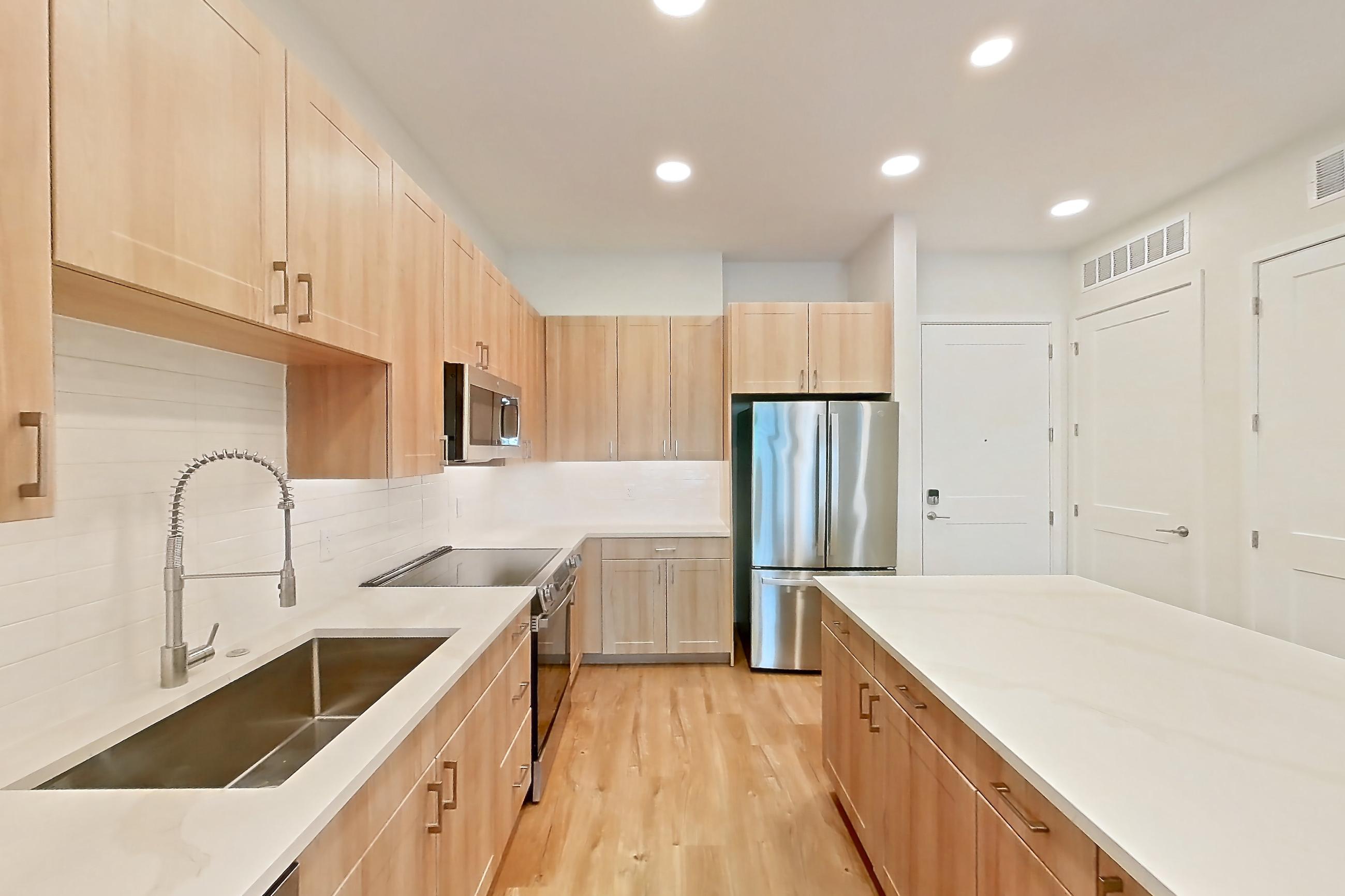 Kitchen with dishwasher, electric range, light countertops, light stone countertops, light wood-finish flooring, microwave, oven/range, refrigerator, and stainless steel appliances, Apartment 336 at Lantower Bayside