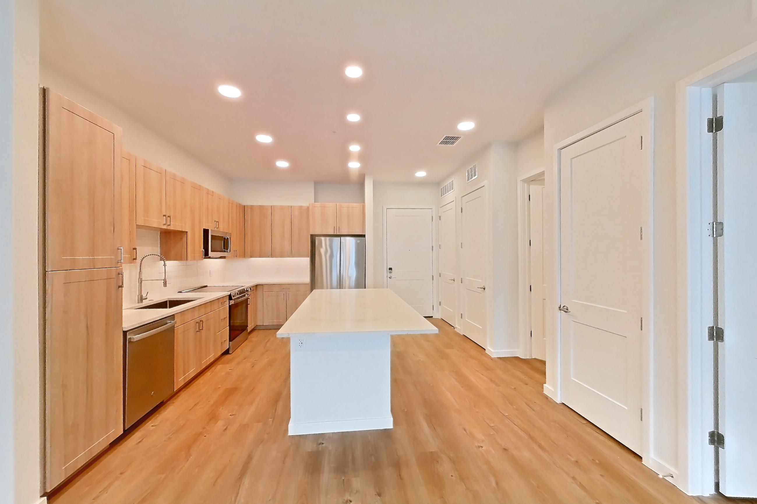 Living space with dishwasher, electric range, light countertops, light stone countertops, light wood-finish flooring, oven/range, refrigerator, and stainless steel appliances, Apartment 336 at Lantower Bayside