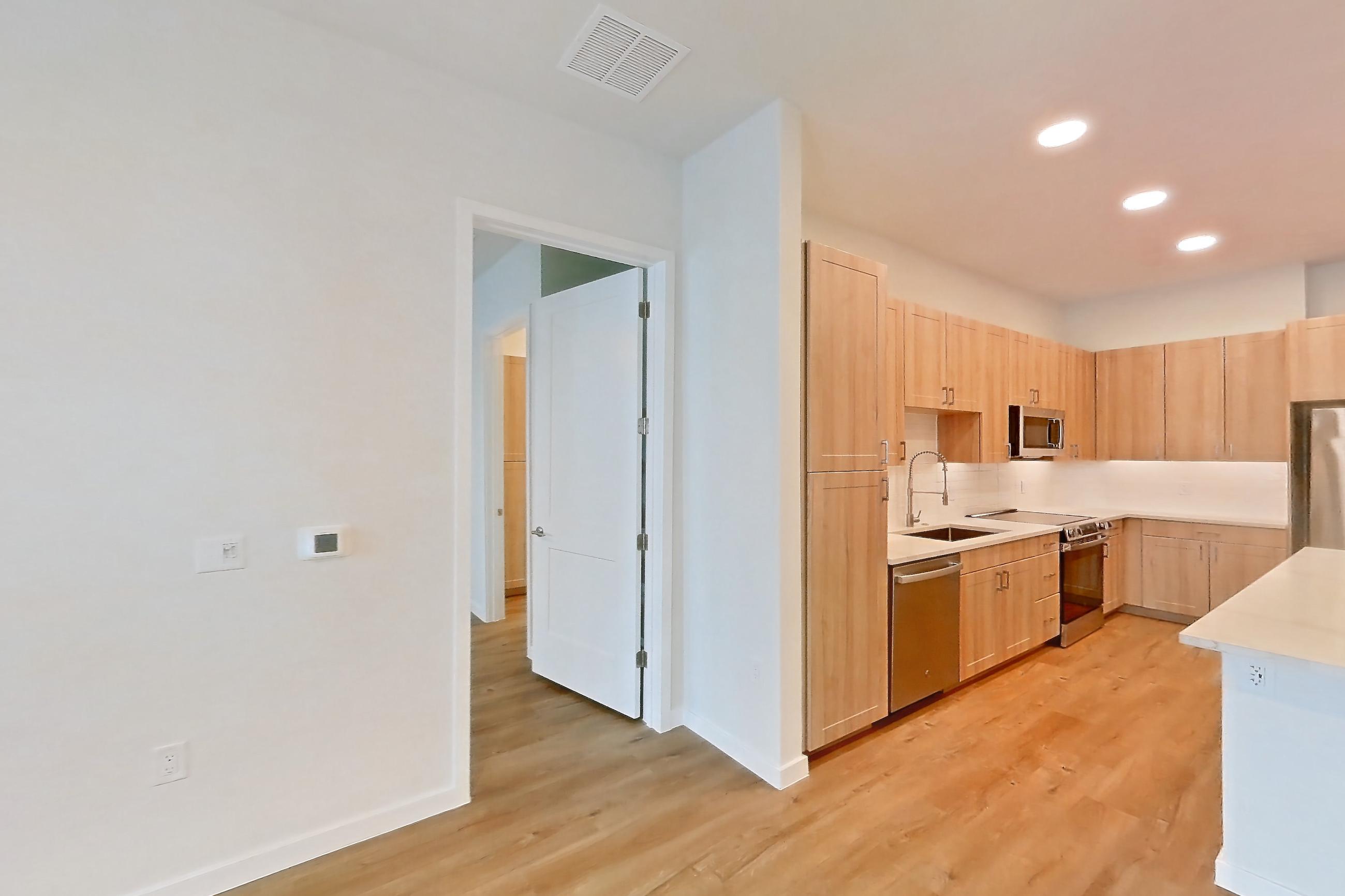 Living space with dishwasher, electric range, light countertops, light stone countertops, light wood-finish flooring, oven/range, refrigerator, and stainless steel appliances, Apartment 336 at Lantower Bayside
