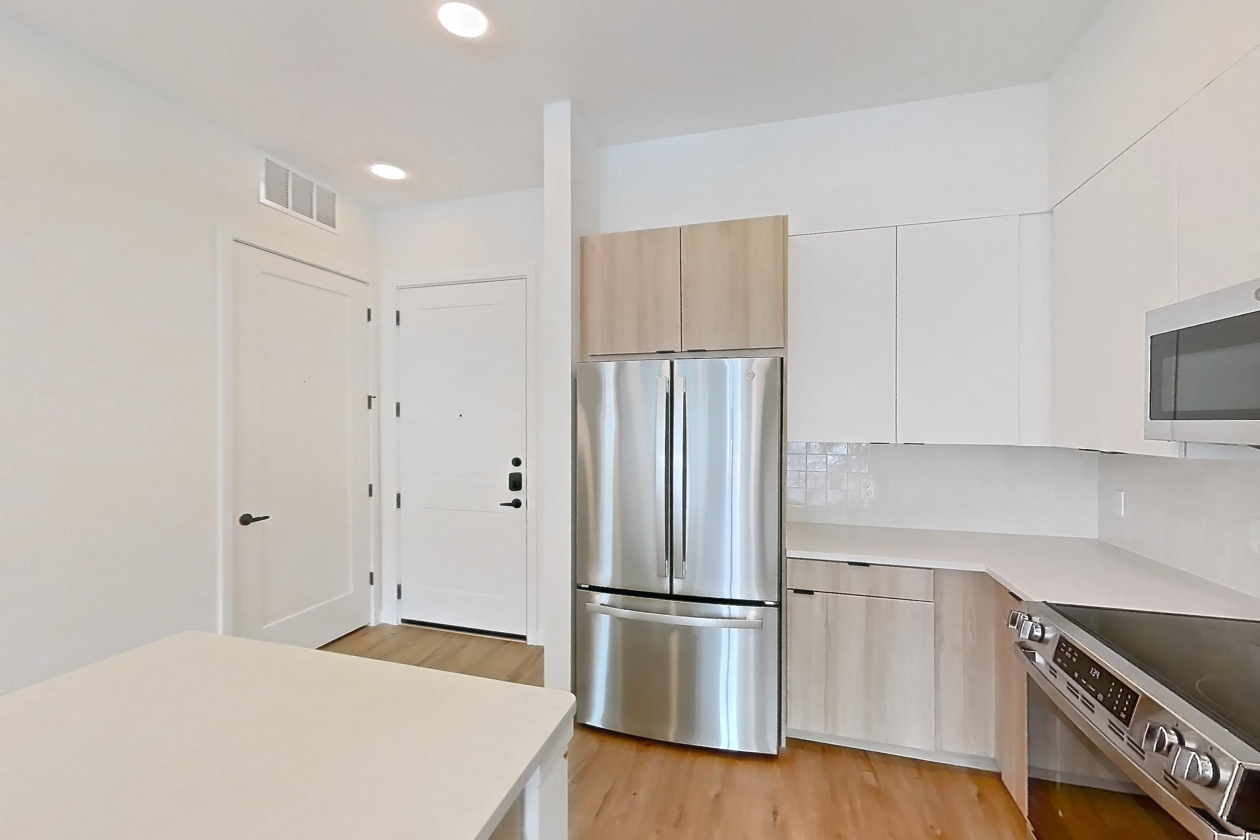 Kitchen with dishwasher, light stone countertops, light wood-finish flooring, refrigerator, and stainless steel appliances, Apartment 146 at Lantower Sunrise
