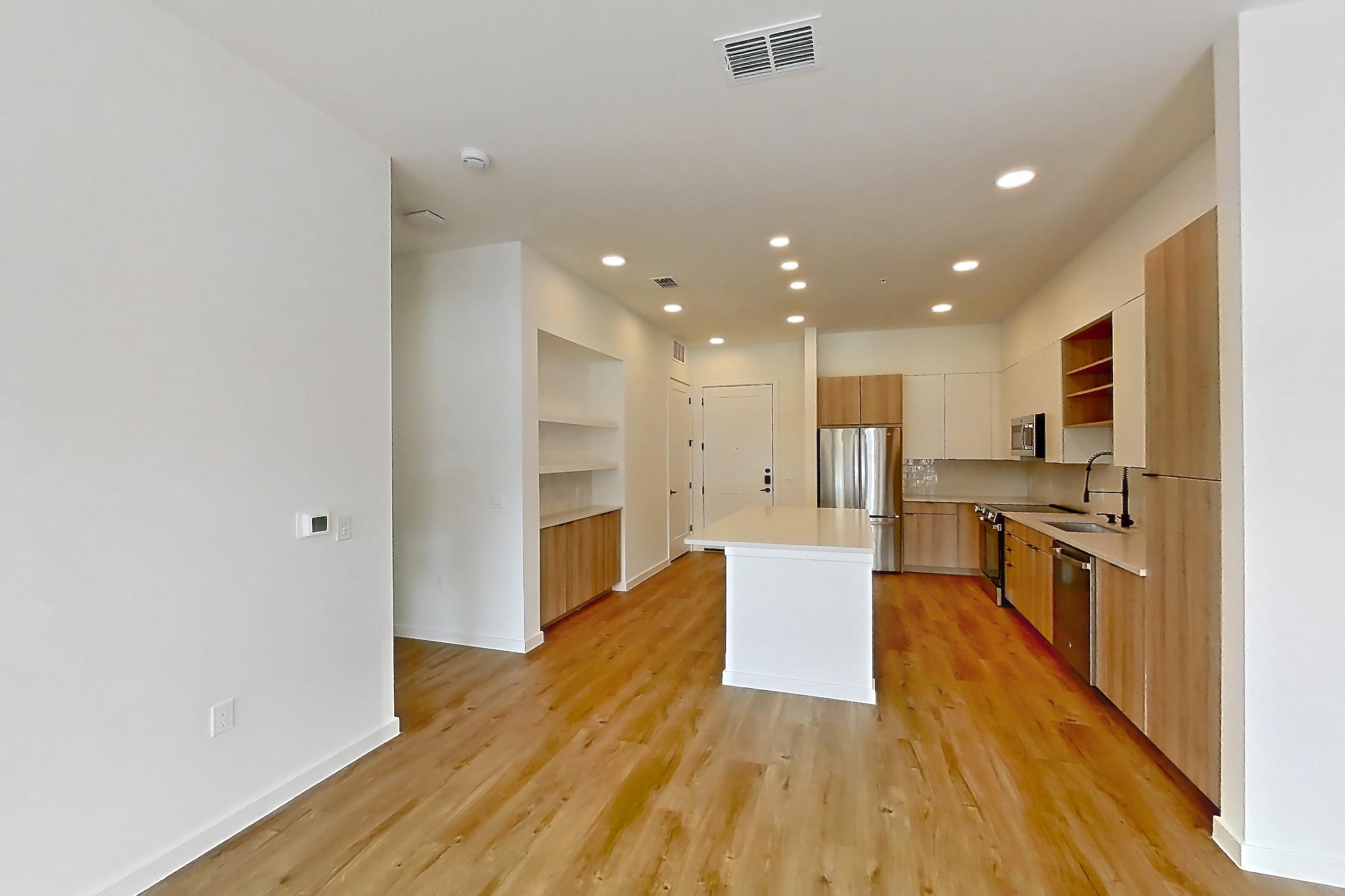 Living room with dishwasher, electric range, light countertops, light wood-finish flooring, oven/range, refrigerator, and stainless steel appliances, Apartment 146 at Lantower Sunrise