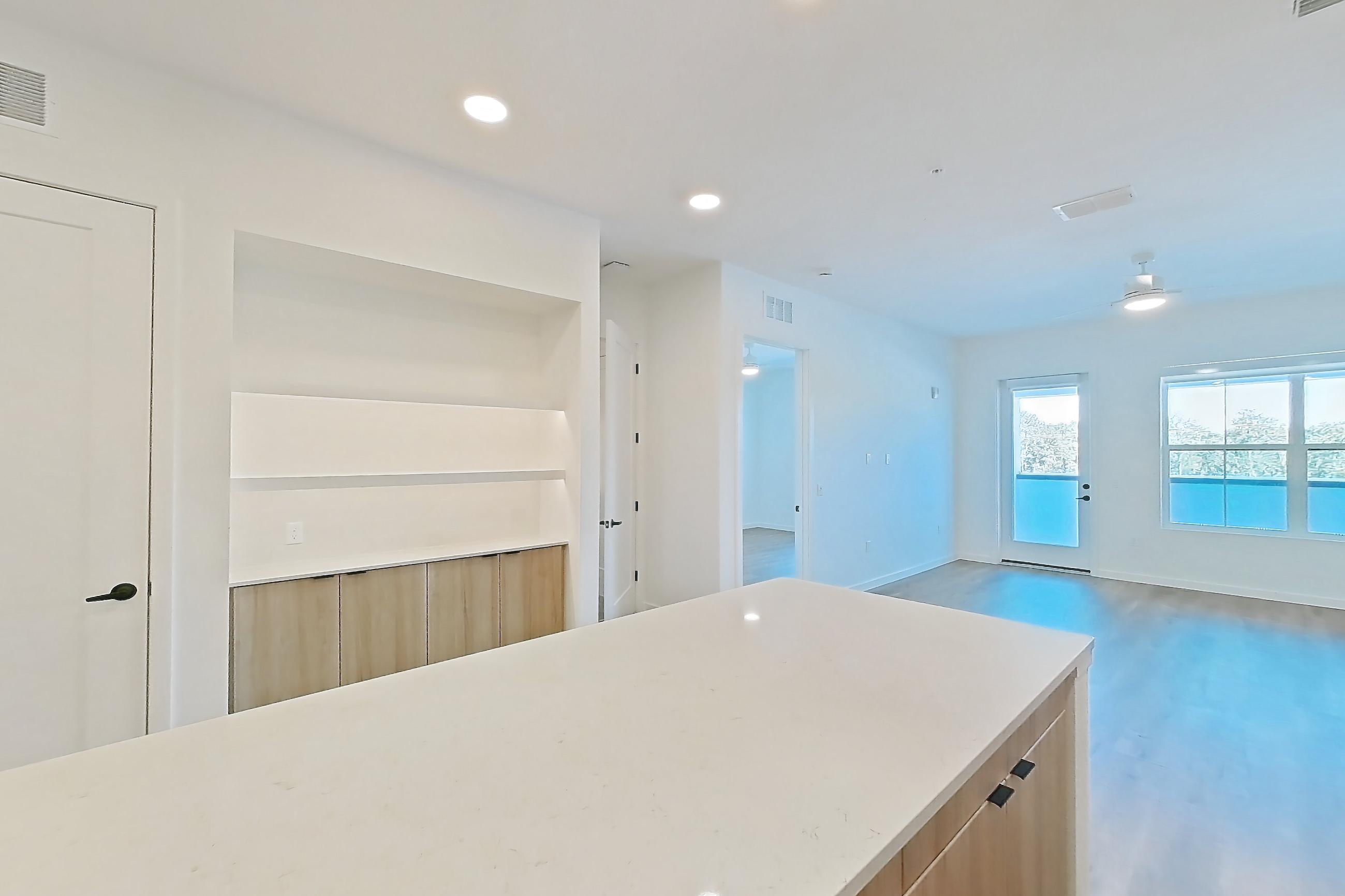 Kitchen with dishwasher, light stone countertops, light wood-finish flooring, refrigerator, and stainless steel appliances, Apartment 318 at Lantower Sunrise