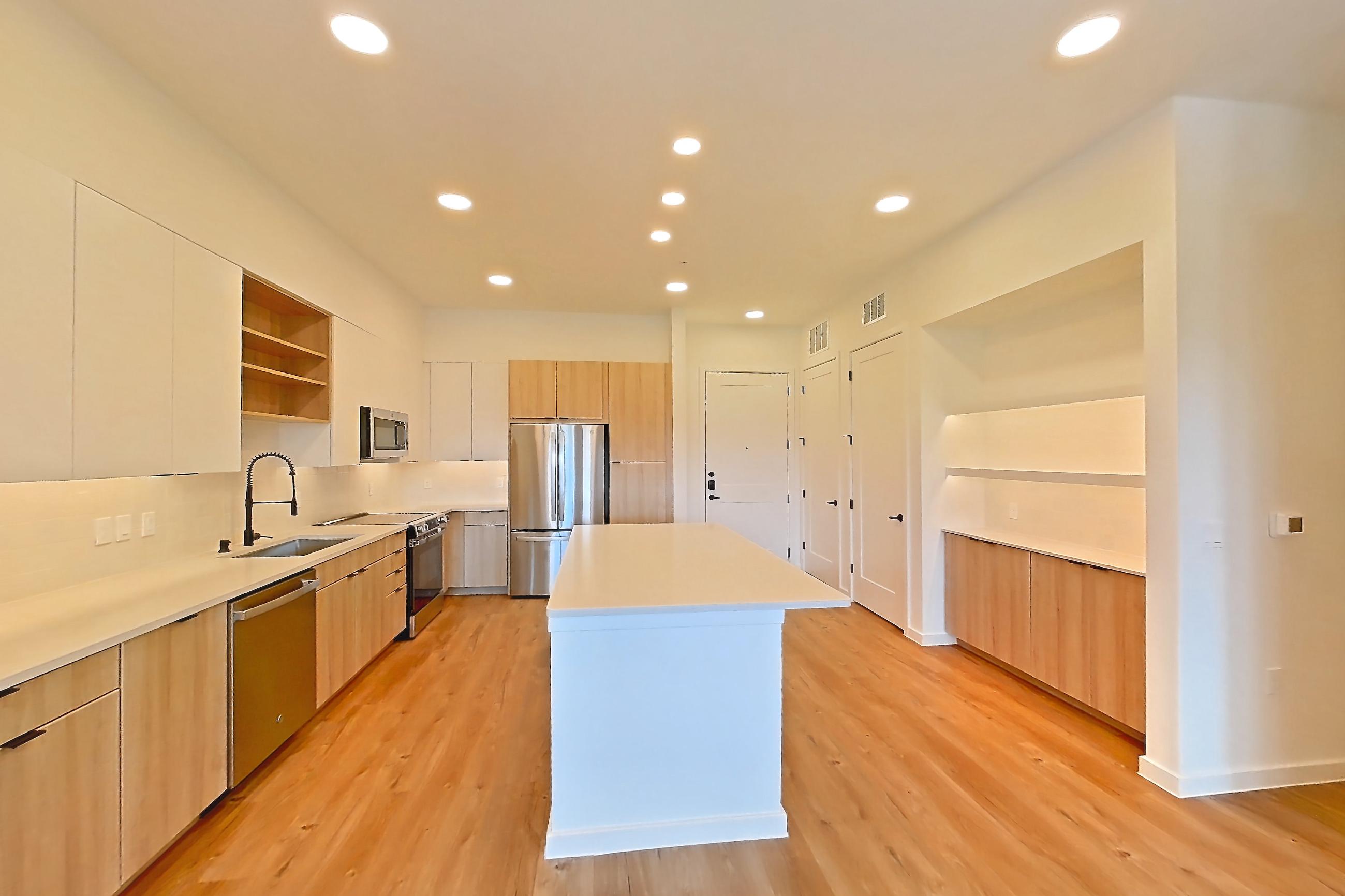 Living room with dishwasher, electric range, light countertops, light wood-finish flooring, oven/range, refrigerator, and stainless steel appliances, Apartment 318 at Lantower Sunrise