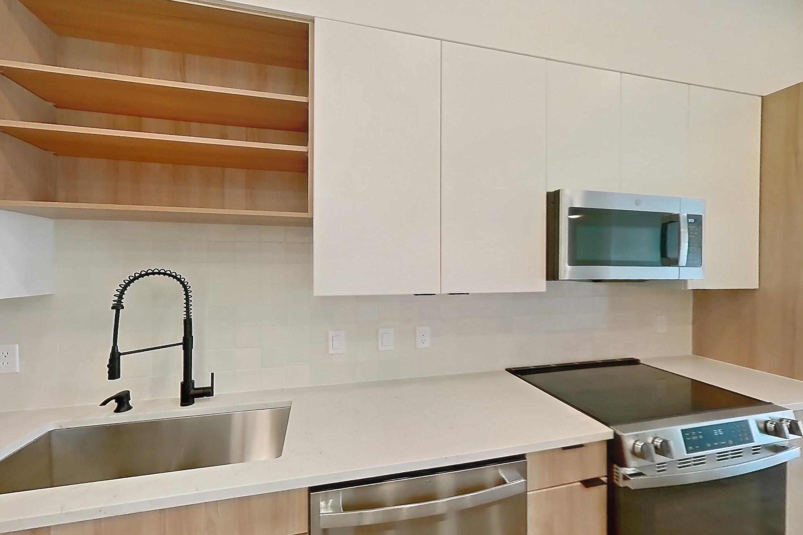 Kitchen with dishwasher, electric range, light stone countertops, light wood-finish flooring, microwave, oven/range, refrigerator, and stainless steel appliances, Apartment 330 at Lantower Sunrise