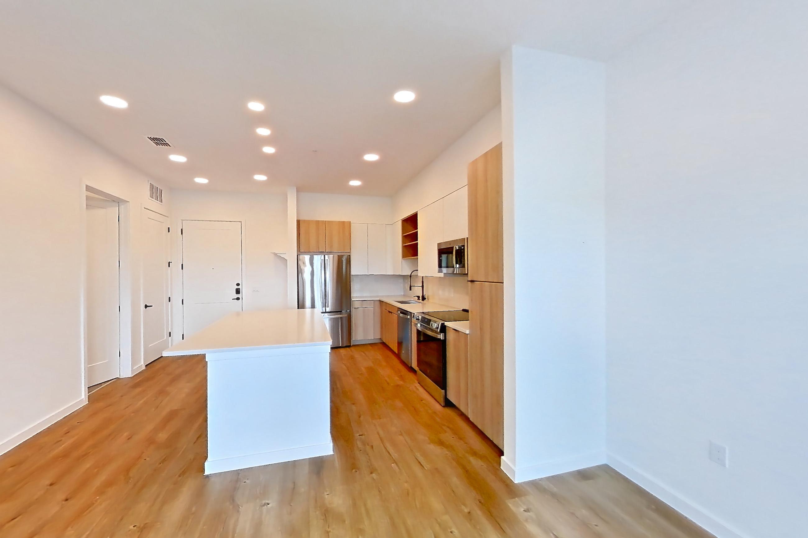 Living room with dishwasher, electric range, light countertops, light wood-finish flooring, oven/range, refrigerator, and stainless steel appliances, Apartment 330 at Lantower Sunrise