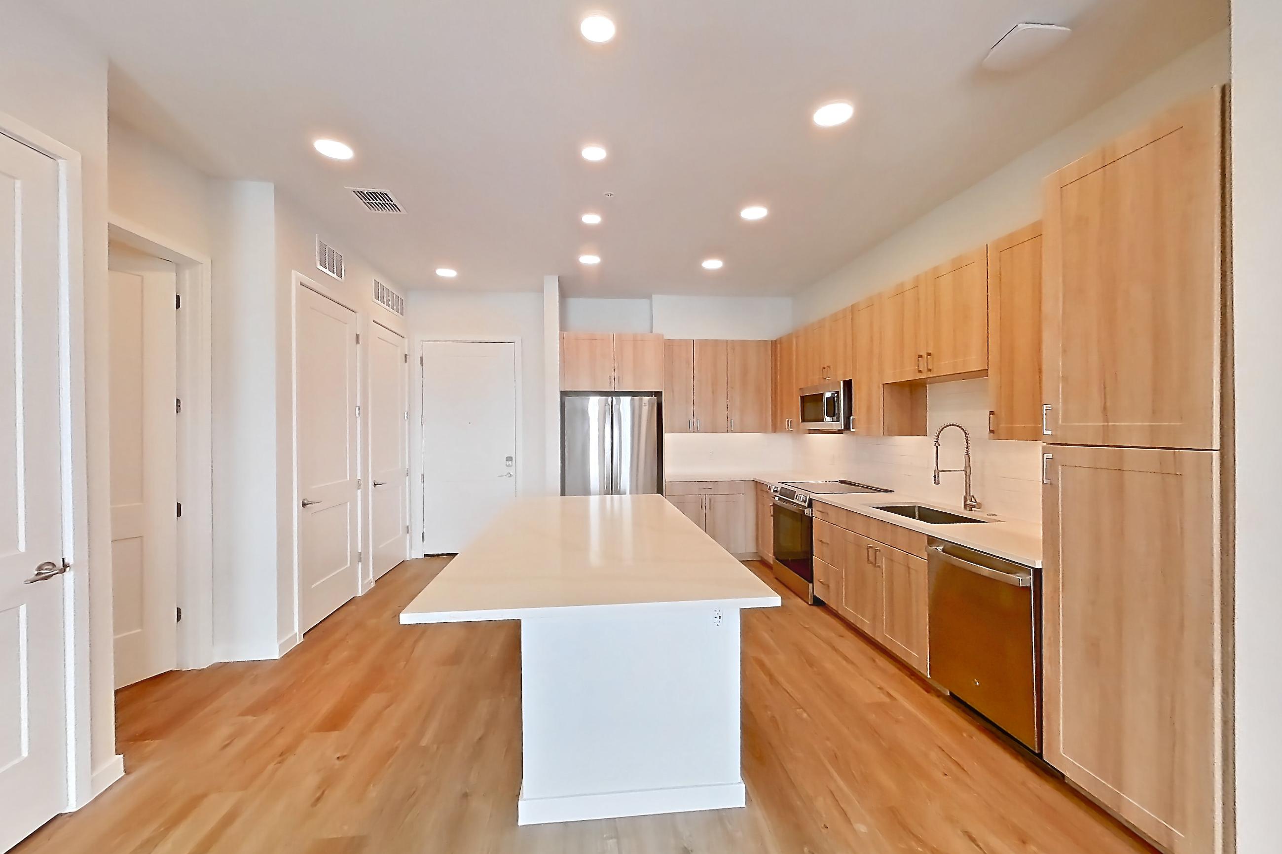 Living space with dishwasher, electric range, light countertops, light wood-finish flooring, oven/range, refrigerator, and stainless steel appliances, Apartment 435 at Lantower Bayside