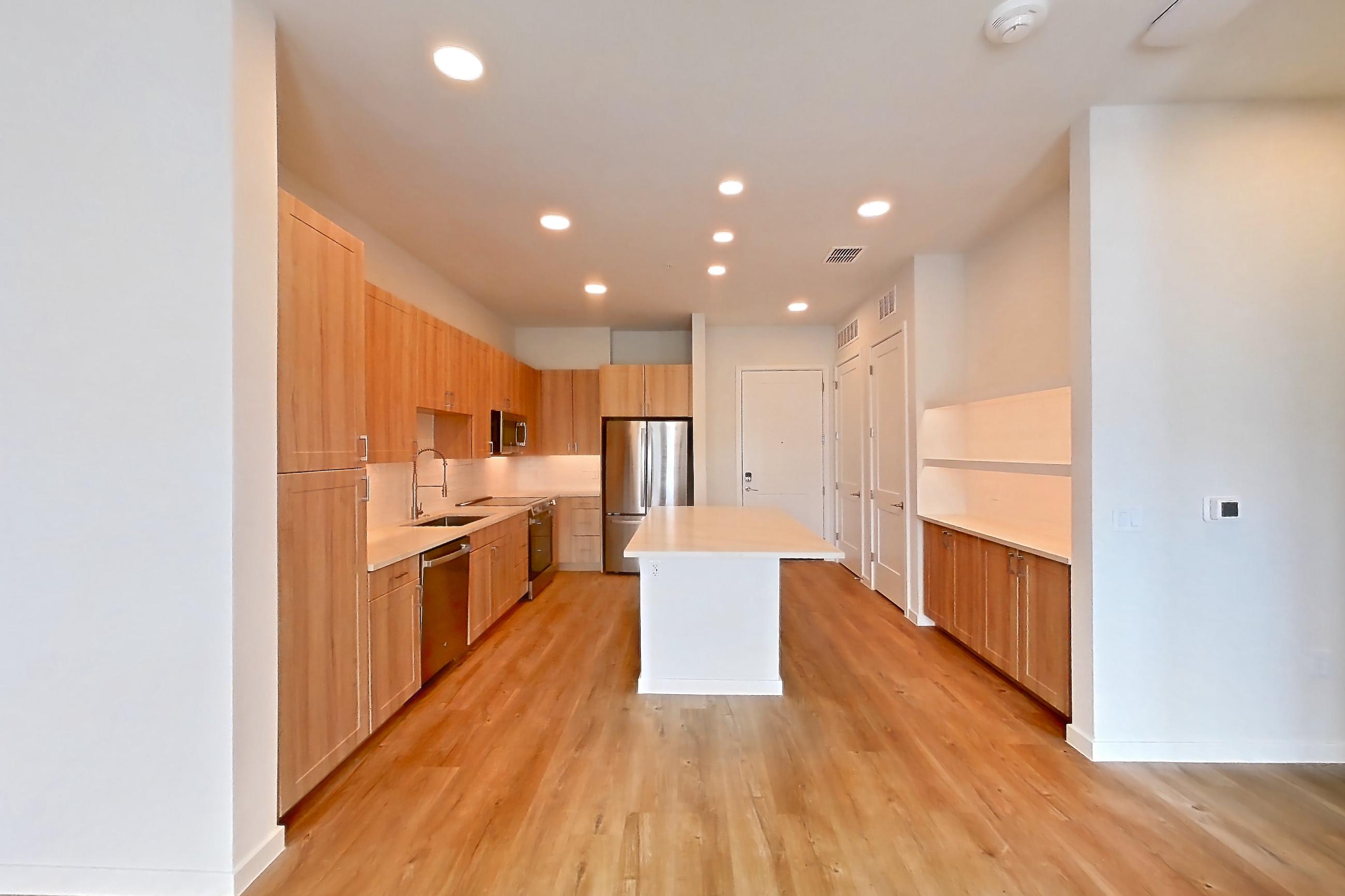 Living space with dishwasher, light countertops, light wood-finish flooring, oven/range, refrigerator, and stainless steel appliances, Apartment 438 at Lantower Bayside
