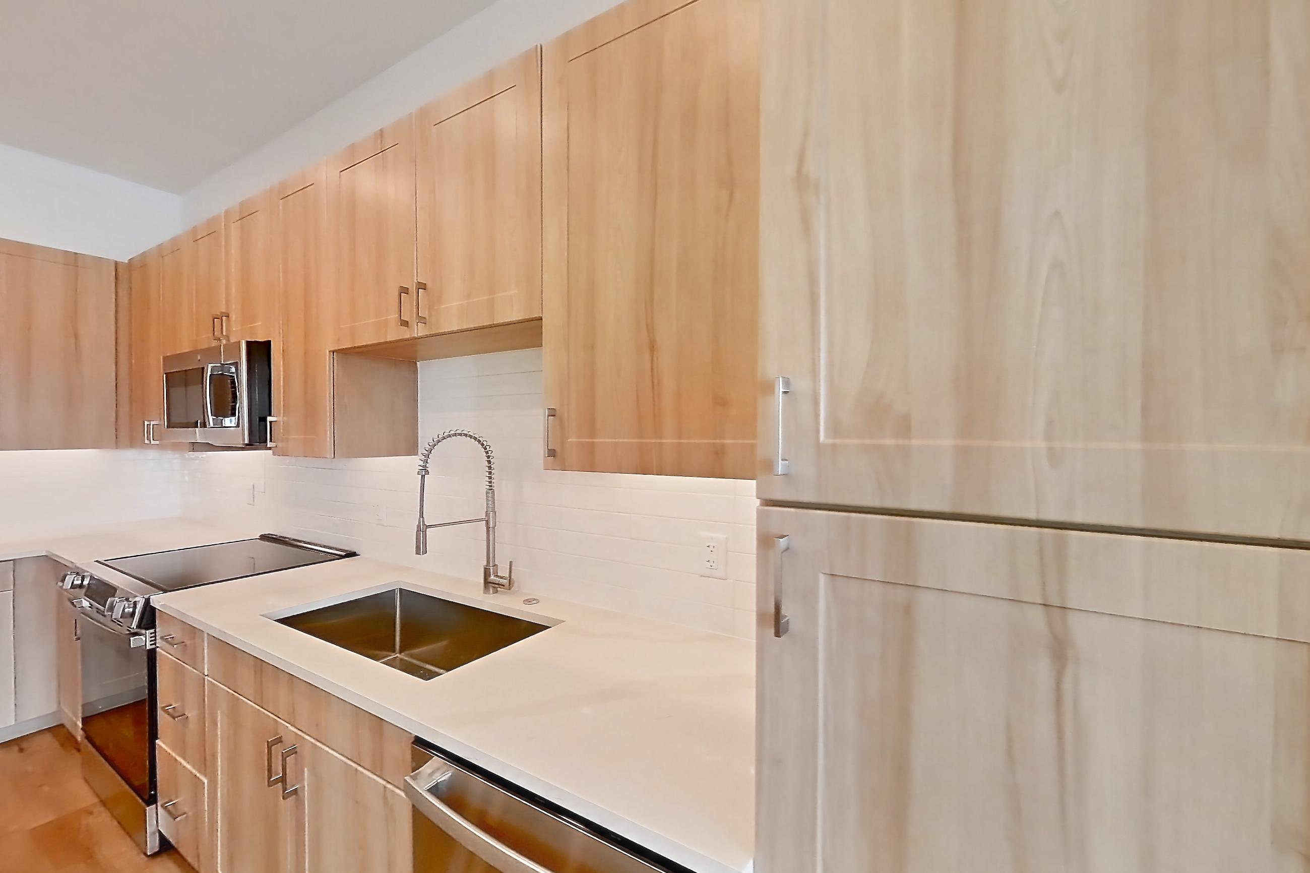 Kitchen with dishwasher, electric range, light countertops, light stone countertops, light wood-finish flooring, oven/range, refrigerator, and stainless steel appliances, Apartment 442 at Lantower Bayside