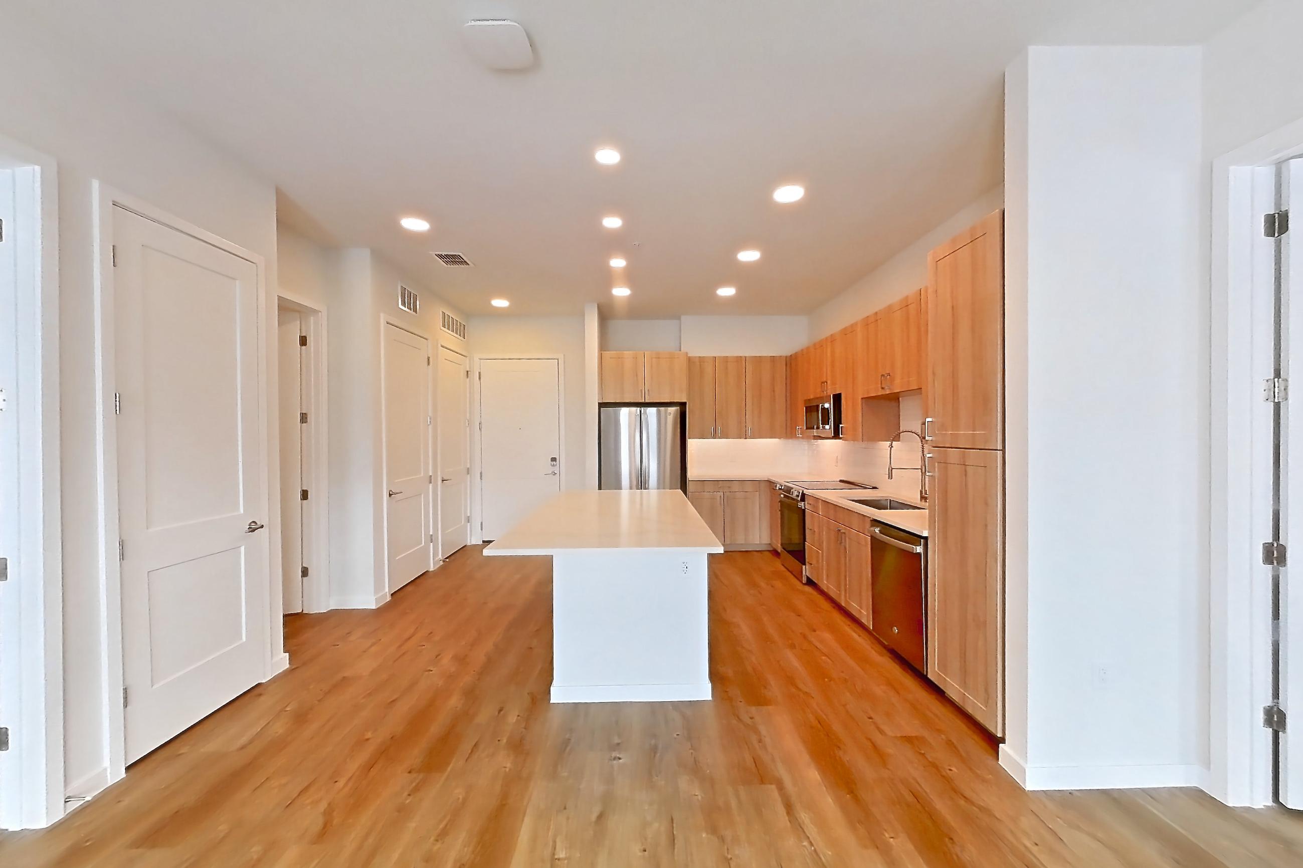 Living space with dishwasher, electric range, light countertops, light wood-finish flooring, oven/range, refrigerator, and stainless steel appliances, Apartment 442 at Lantower Bayside