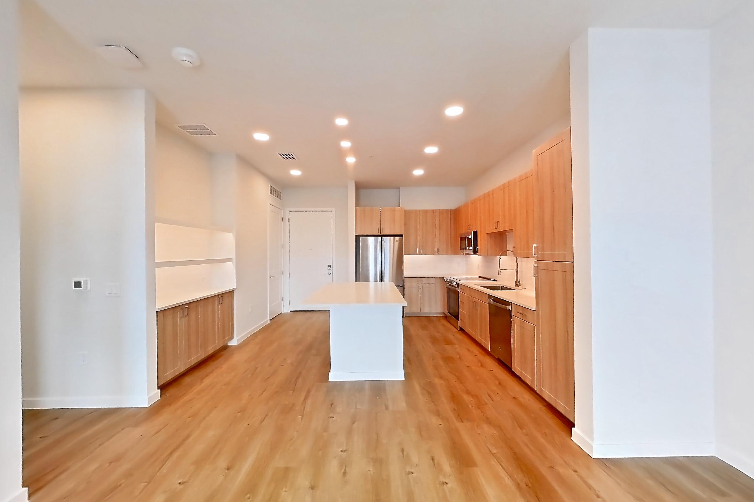 Living space with dishwasher, electric range, light countertops, light wood-finish flooring, oven/range, refrigerator, and stainless steel appliances, Apartment 446 at Lantower Bayside