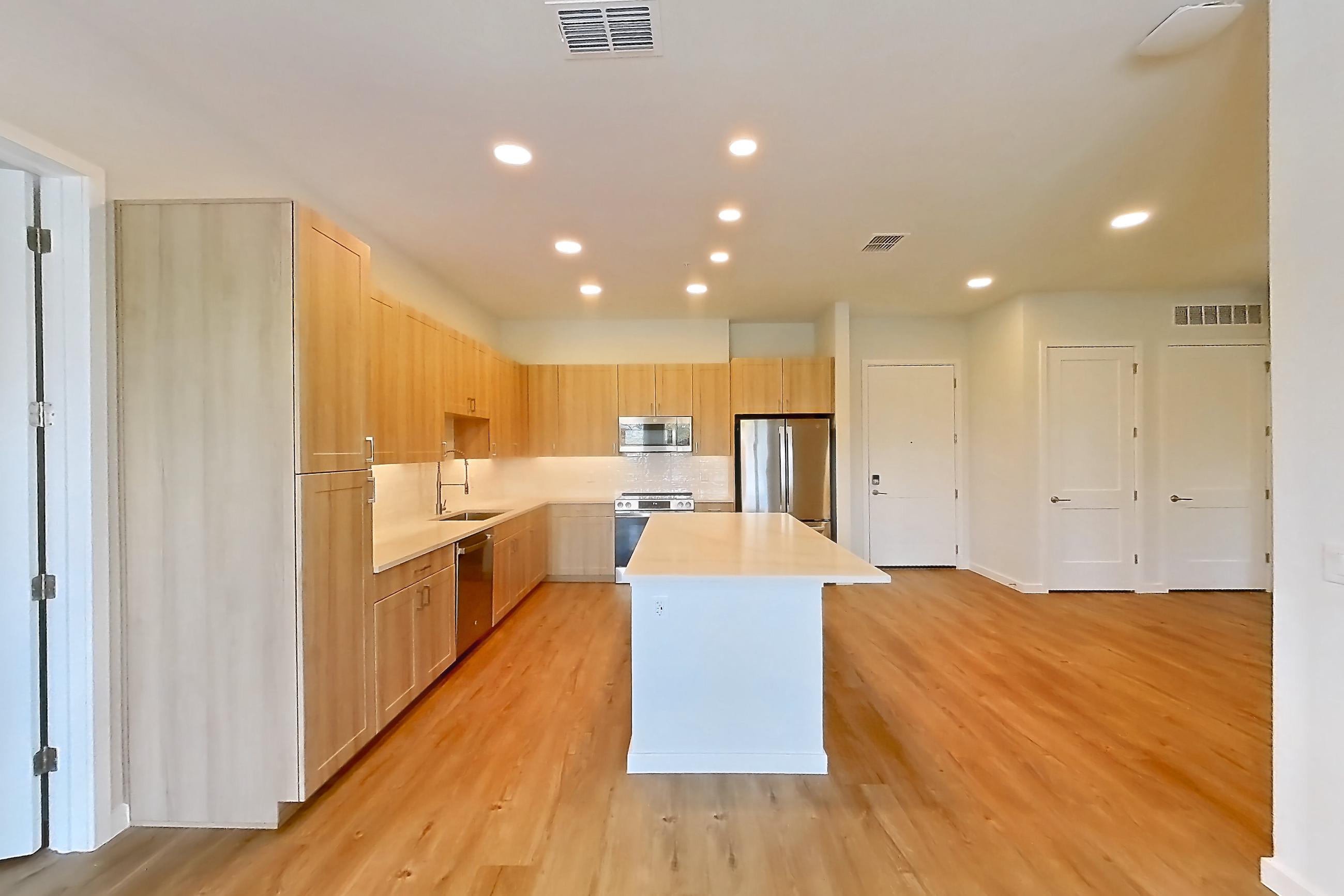 Living space with dishwasher, light countertops, light wood-finish flooring, oven/range, refrigerator, and stainless steel appliances, Apartment 449 at Lantower Bayside