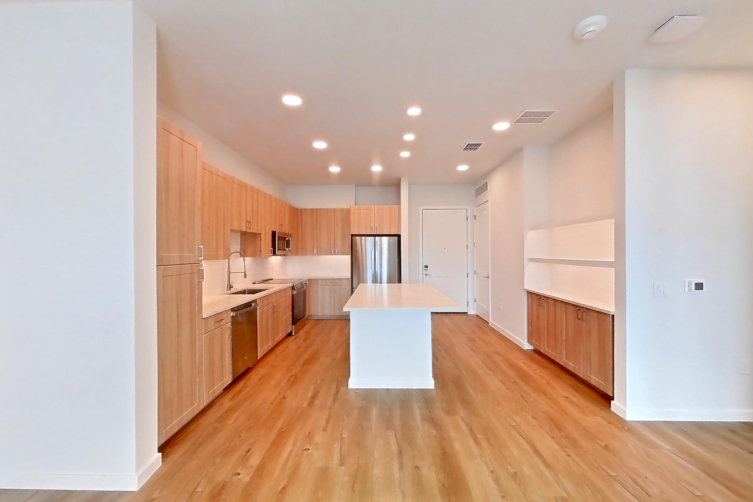 Living space with dishwasher, electric range, light countertops, light wood-finish flooring, oven/range, refrigerator, and stainless steel appliances, Apartment 450 at Lantower Bayside
