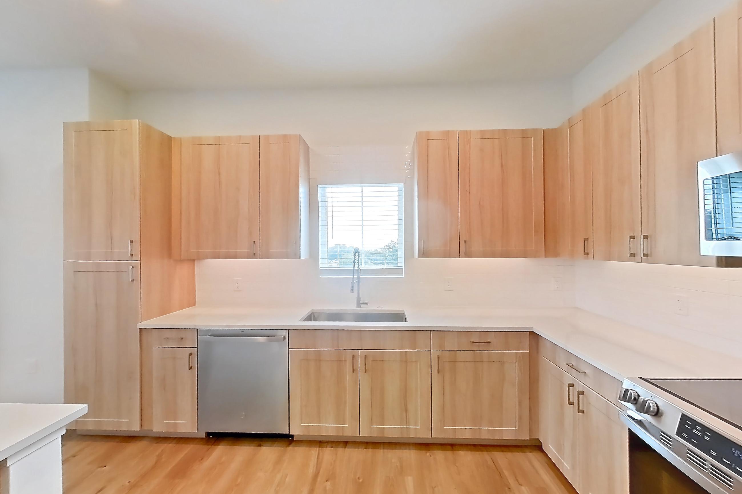 Kitchen with dishwasher, electric range, light countertops, light wood-finish flooring, microwave, oven/range, refrigerator, and stainless steel appliances, Apartment 453 at Lantower Bayside