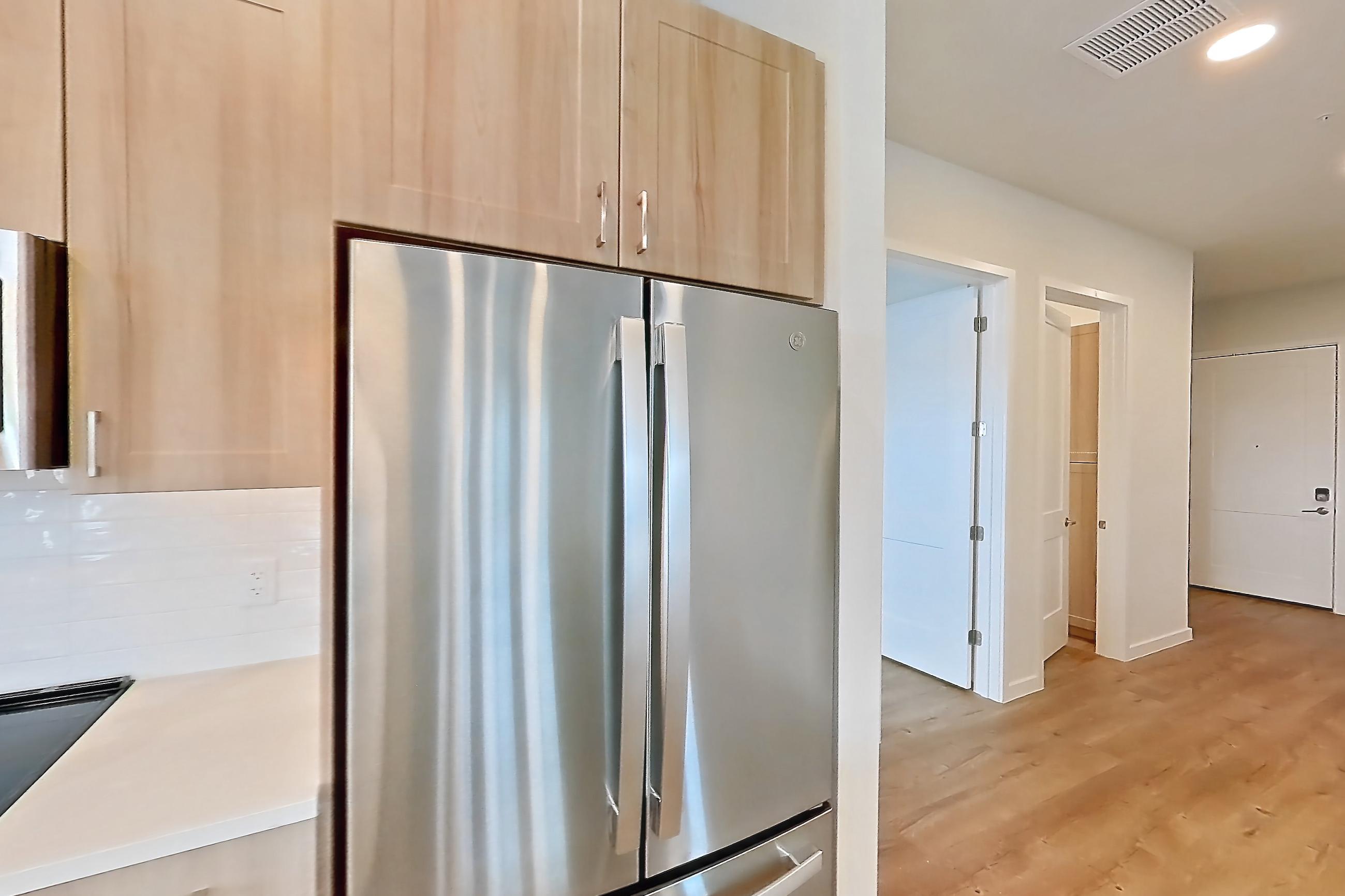 Kitchen with dishwasher, electric range, light countertops, light wood-finish flooring, microwave, oven/range, refrigerator, and stainless steel appliances, Apartment 453 at Lantower Bayside