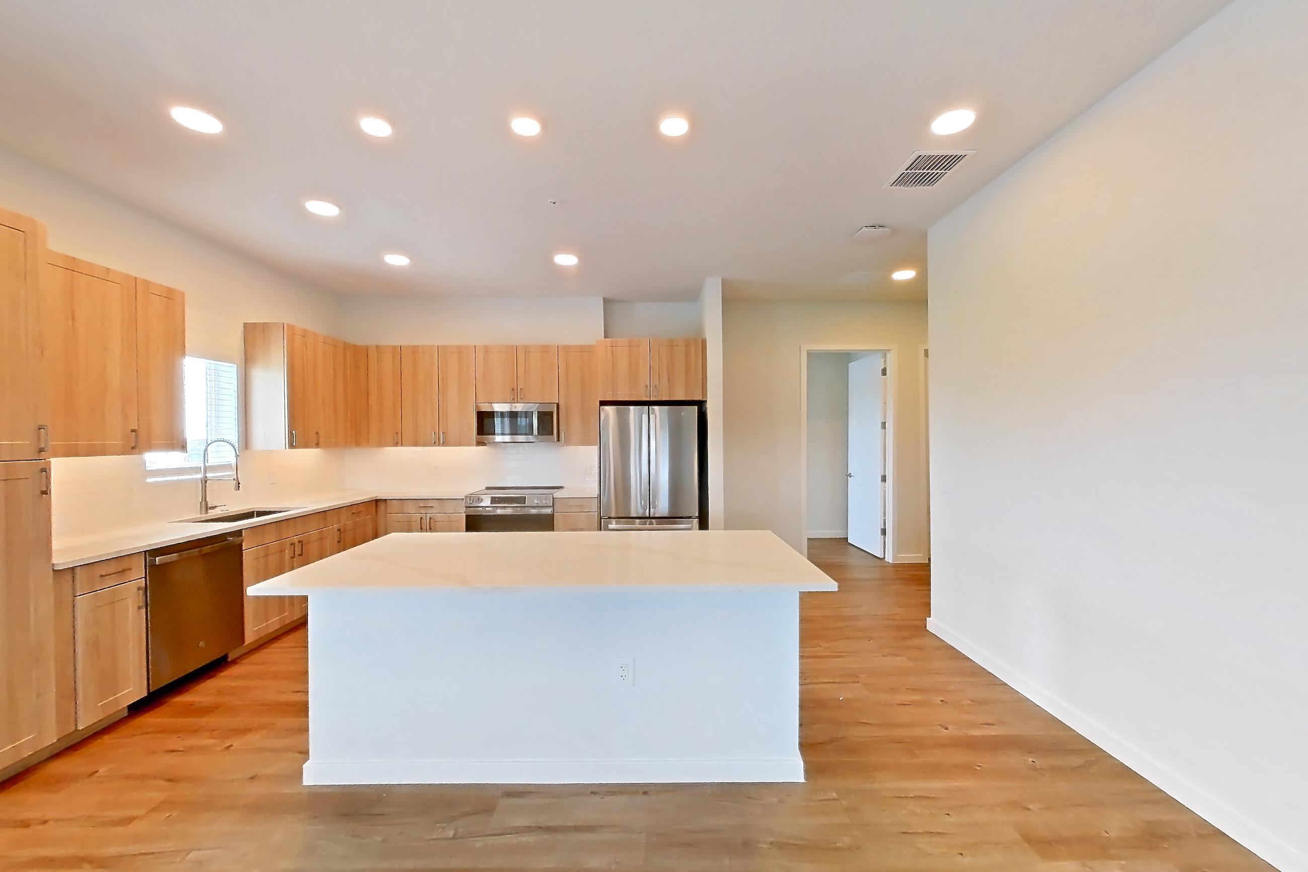 Living space with dishwasher, electric range, light countertops, light wood-finish flooring, oven/range, refrigerator, and stainless steel appliances, Apartment 453 at Lantower Bayside