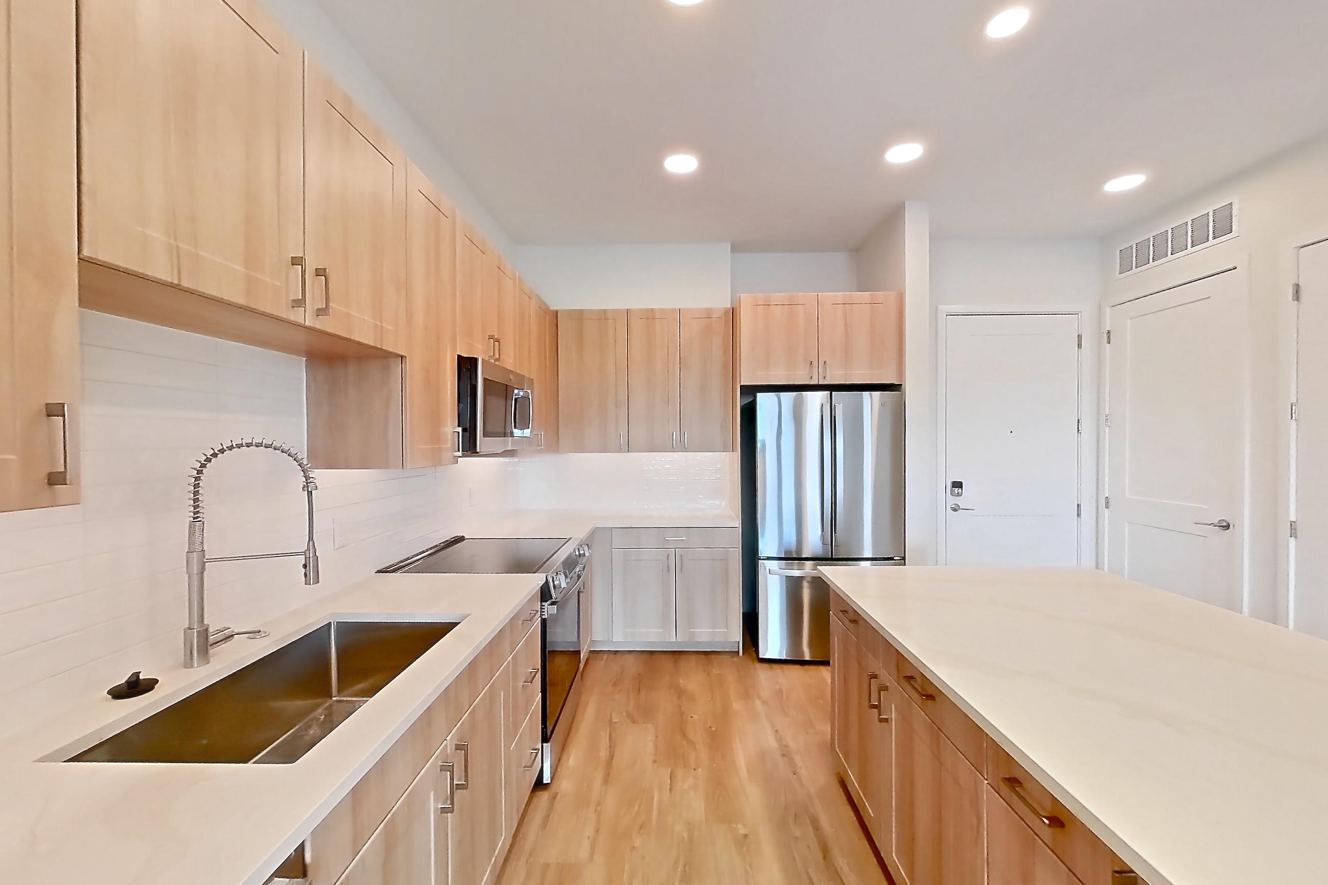 Kitchen with dishwasher, electric range, light countertops, light stone countertops, light wood-finish flooring, oven/range, refrigerator, and stainless steel appliances, Apartment 454 at Lantower Bayside